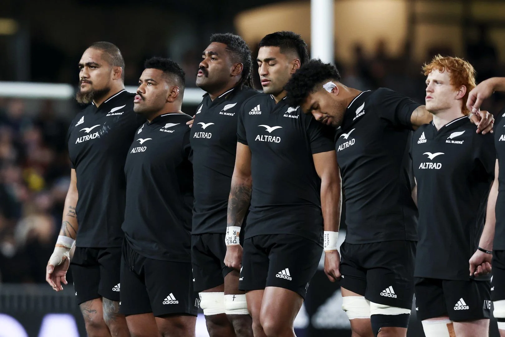 A group of rugby players standing in a line during a game, wearing black jerseys with the 'All Blacks' logo and sponsor 'Altrad'.