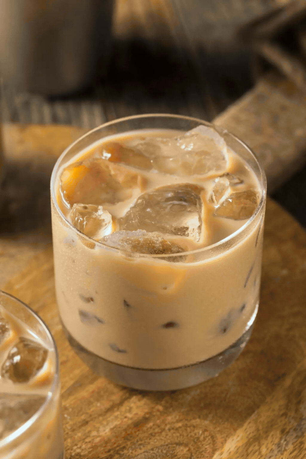 Un verre de café au lait glacé avec des glaçons, posé sur une table en bois.