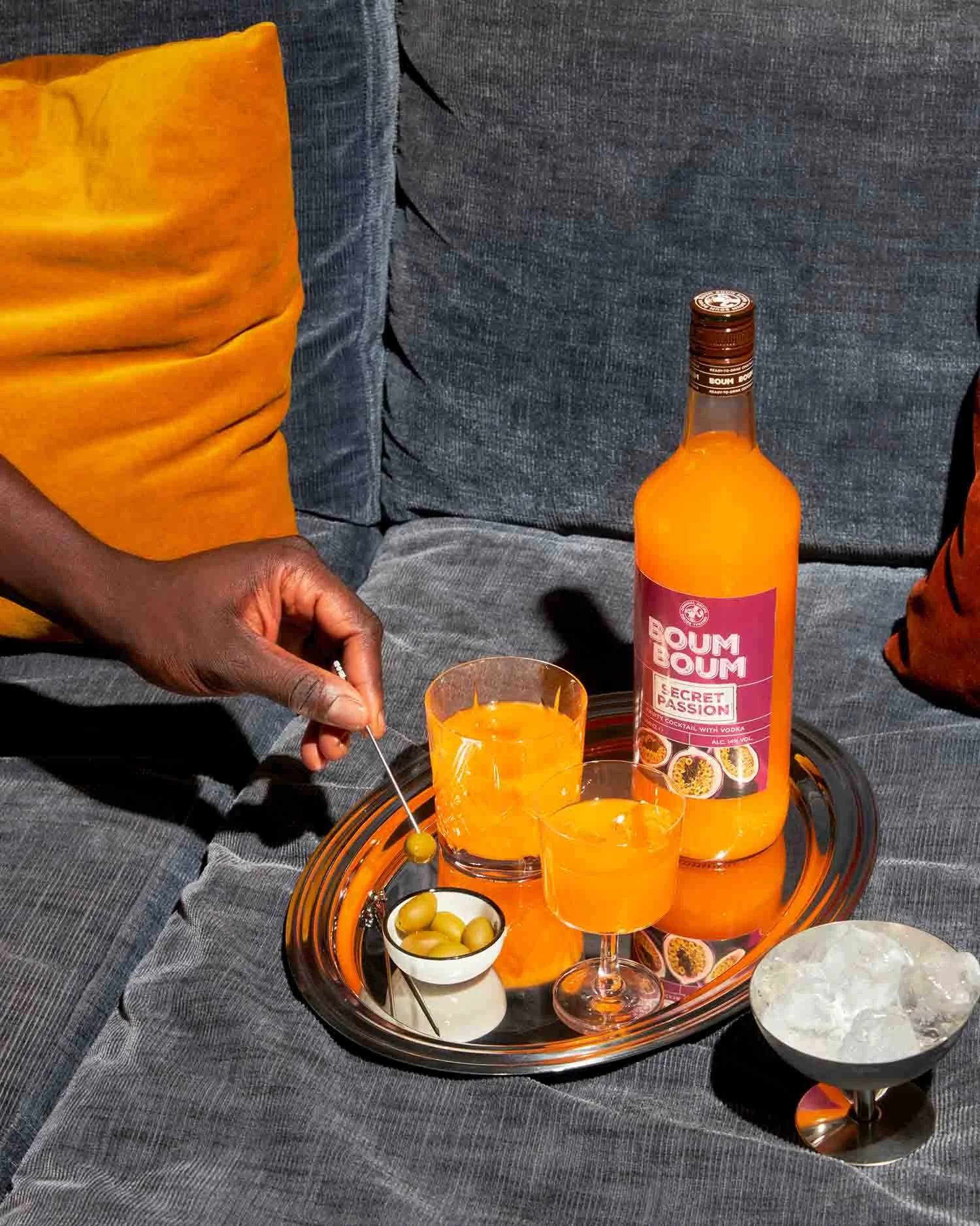 Groupe de personnes partageant un moment convivial autour d'une table avec des boissons orange et des olives, avec un flacon de sirop à côtés.