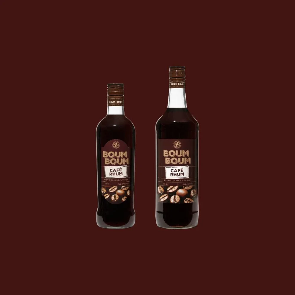 Deux bouteilles de sirop ou boisson aromatisée au café et rhum de la marque Boum Boum, avec étiquettes illustrant des grains de café, contre un fond marron.