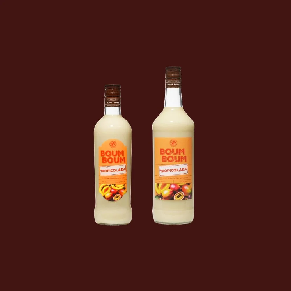 Deux bouteilles de boisson tropicale Boum Boum Tropicolada avec des fruits tropicaux sur l'étiquette, sur un fond marron.