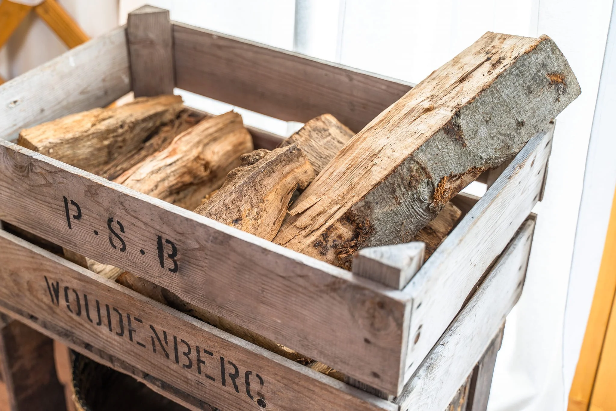 Wooden crate filled with firewood logs, labeled with 'P. S. 13' and 'WOULD-NB-ER.C'.