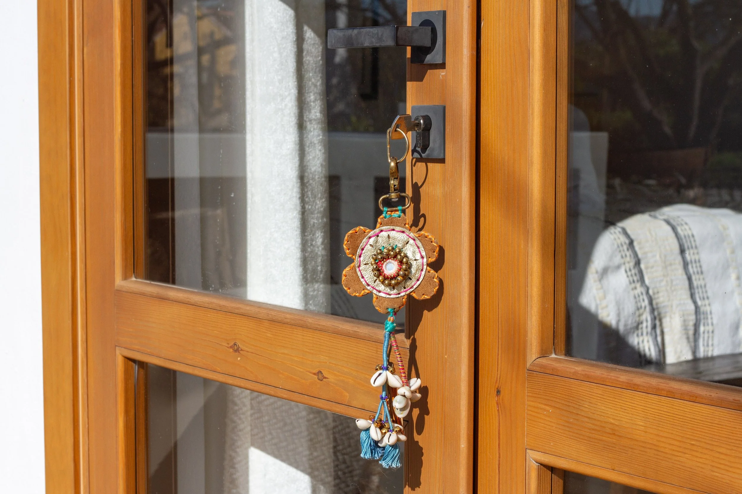 Decorative keychain hanging on a door handle of a wooden door with glass panes