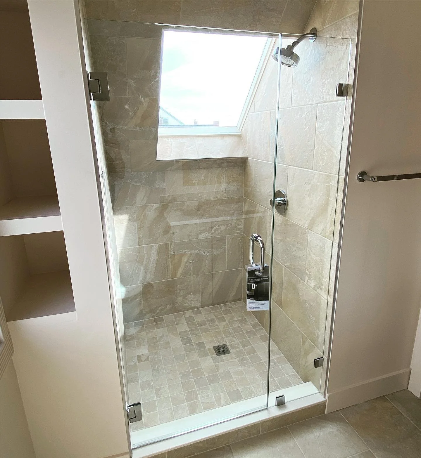 Frameless glass shower door and panel in a narrow tile shower lit by a skylight in a Munjoy Hill, Portland, Maine bathroom