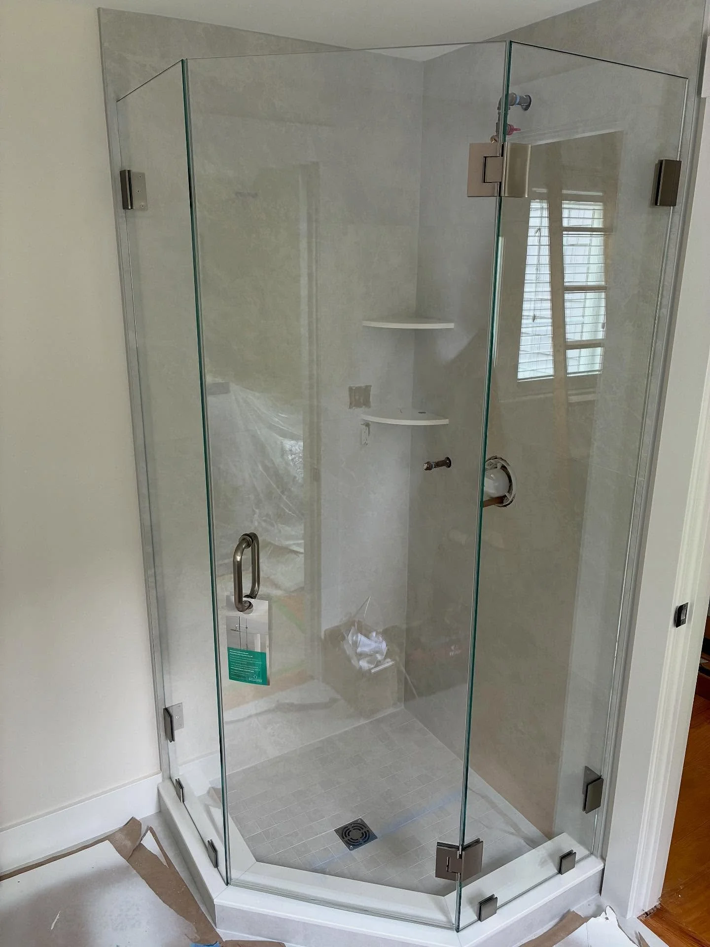 Frameless neo-angle glass shower enclosure with a hinged door and angled panels on a corner base in a Kennebunkport, Maine bathroom