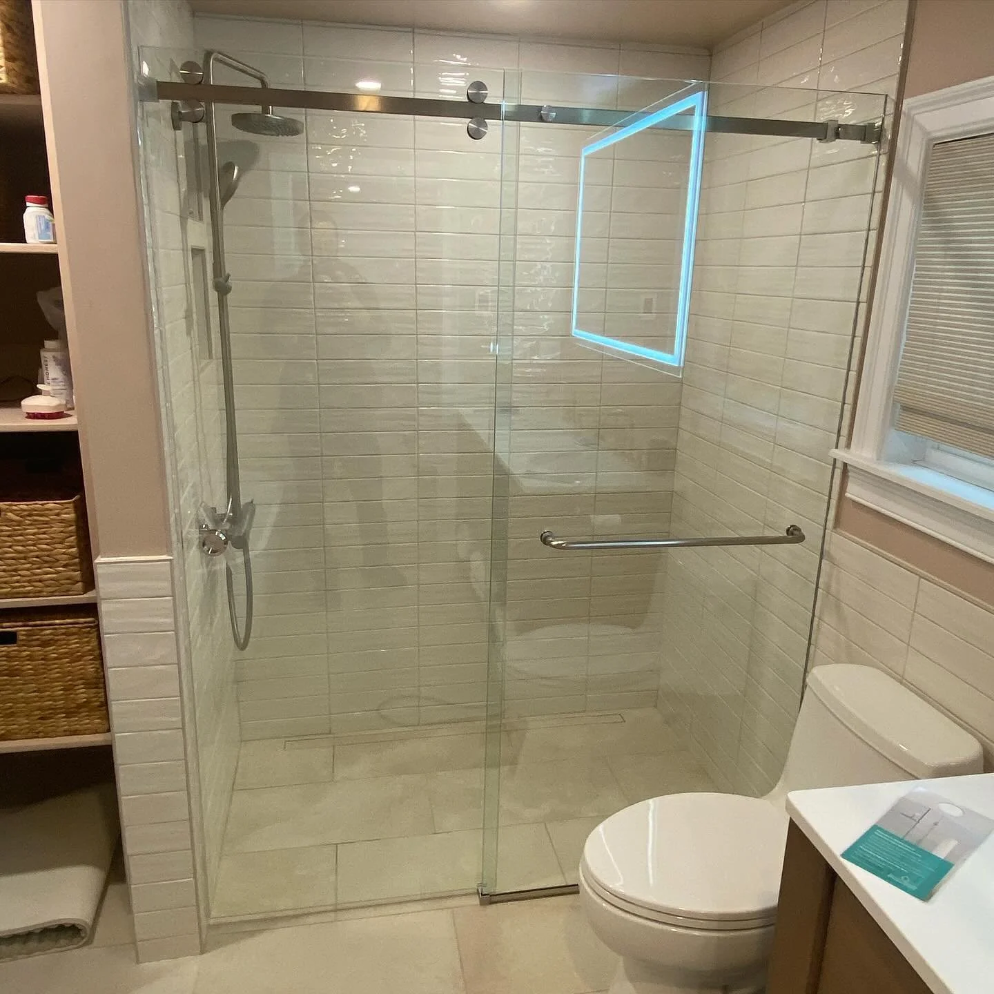 Frameless Serenity sliding glass shower door with a brushed top rail and towel bar over a curbless white-tile shower in a Cape Elizabeth, Maine bathroom