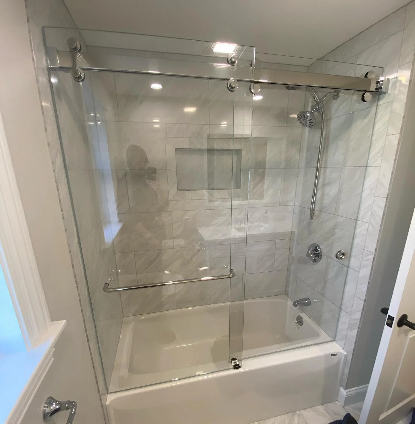 CRL Cambridge heavy-glass bypass sliding doors on a chrome top rolling rail over a tub with a marble-look surround and niche in Biddeford, Maine