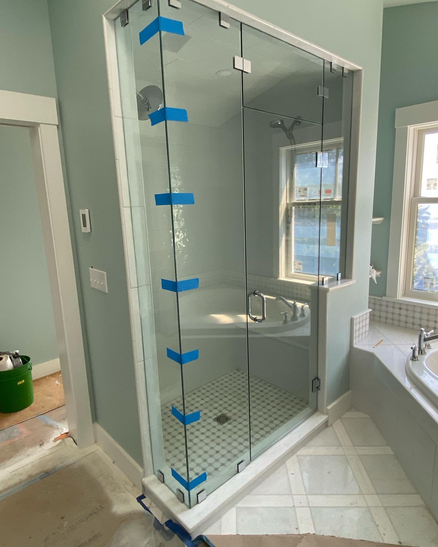Frameless glass corner steam shower enclosure running to the ceiling, with chrome hinges and clips, a hinged door and a panel on a tiled knee wall beside a tub, in a Cousins Island, Yarmouth, Maine bathroom