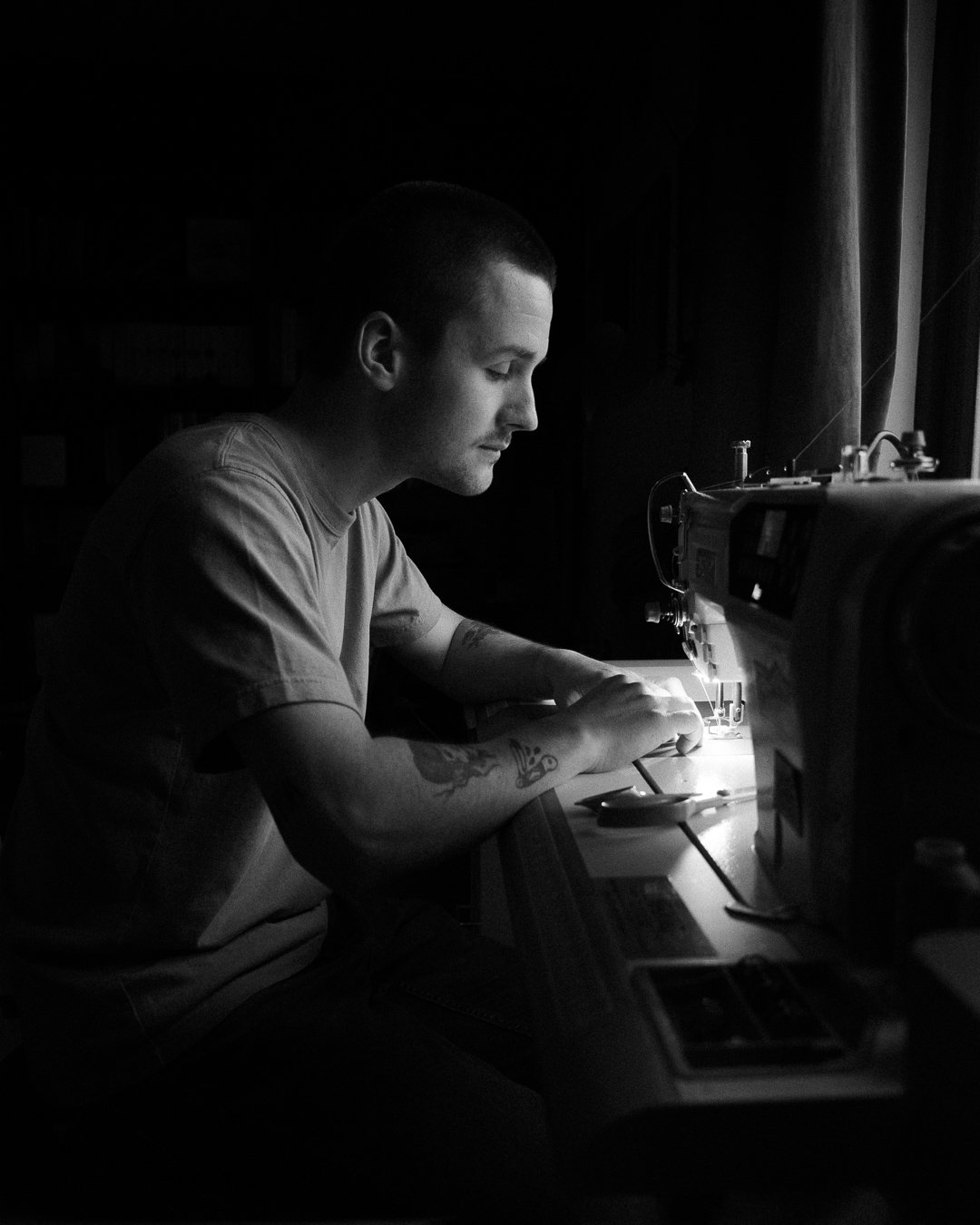 A person sewing with a sewing machine in a dimly lit room.
