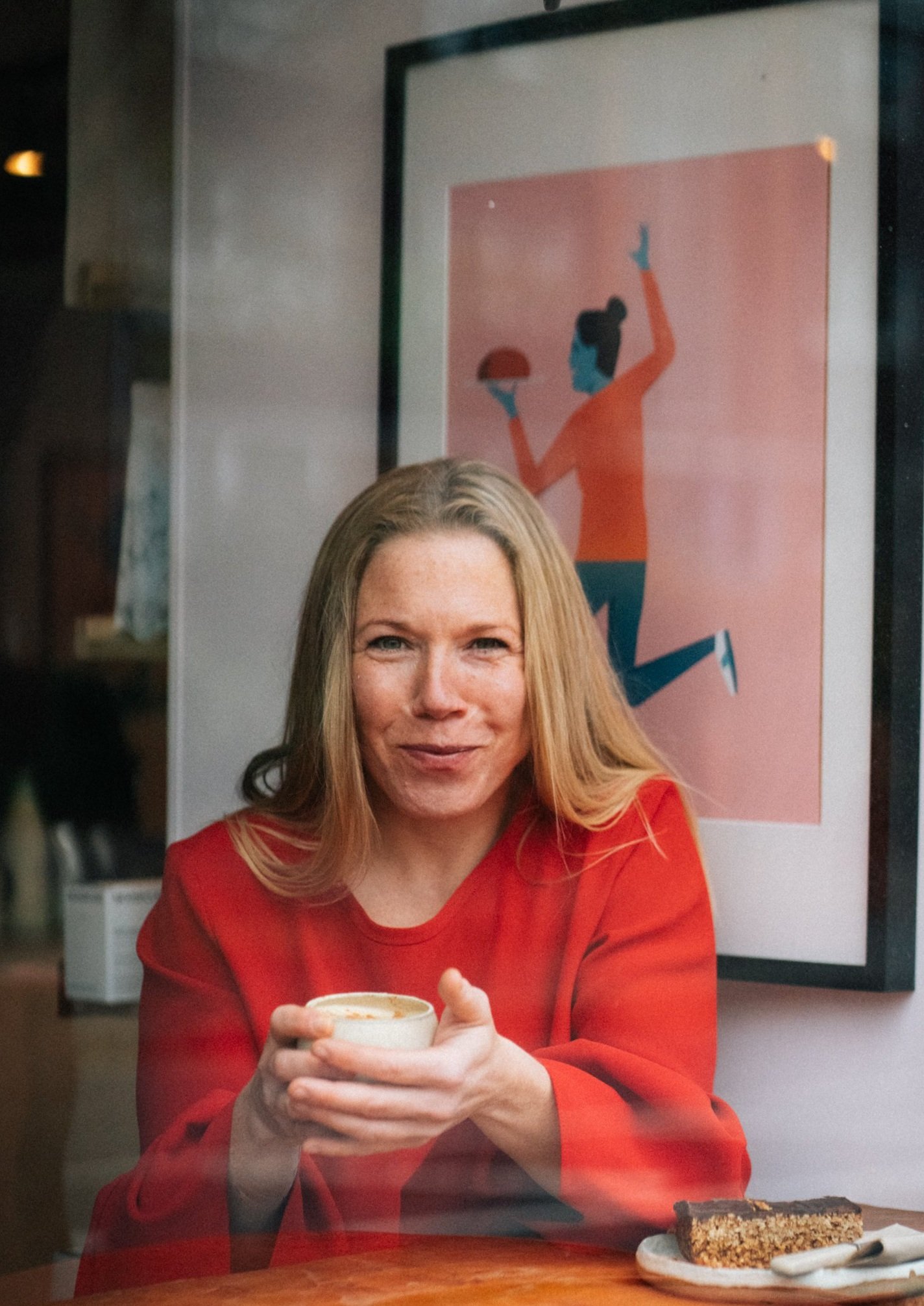 Abi Adams is sitting holding a mug of coffee or tea