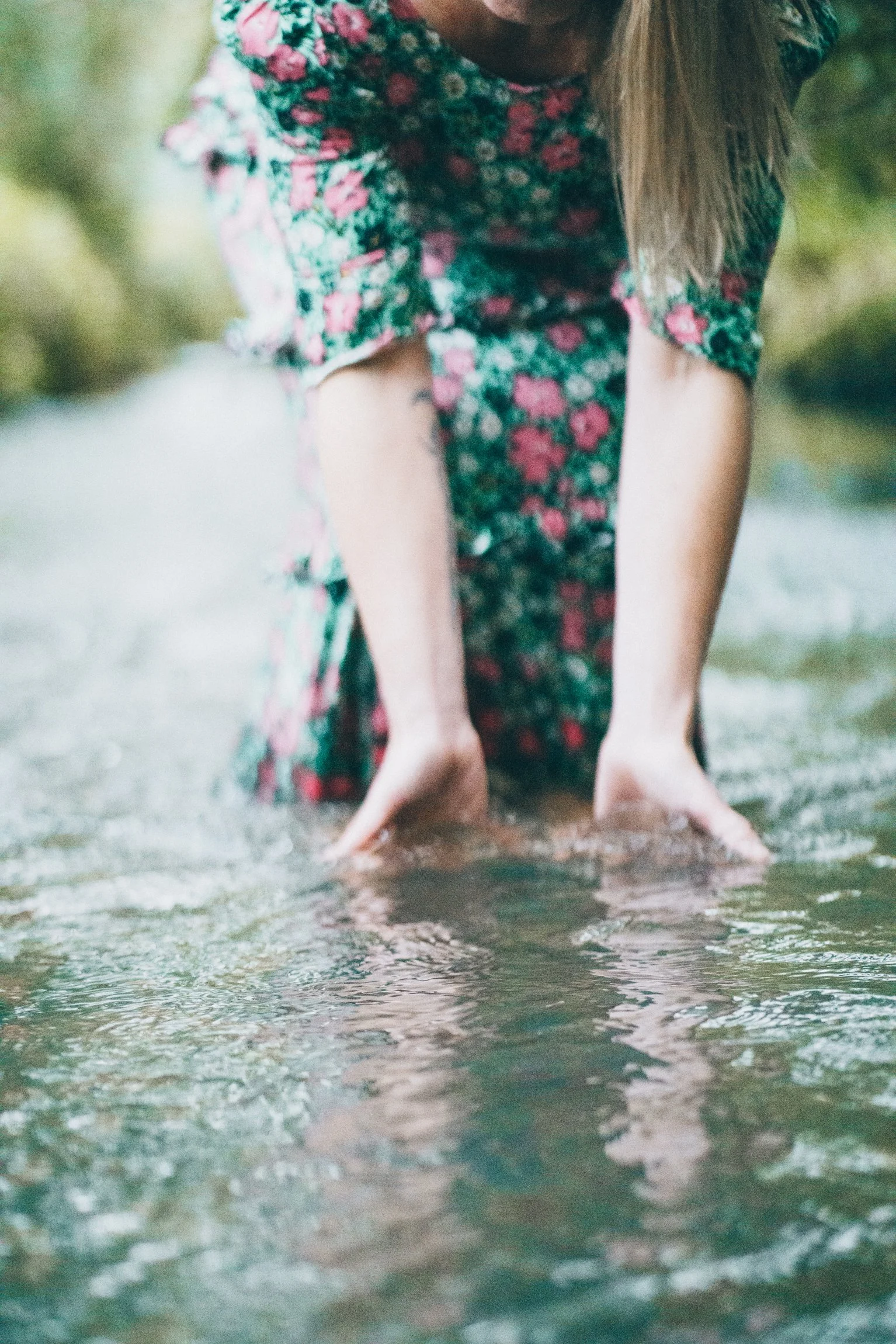 Abi Adams crouching down with her hands in a body of water.