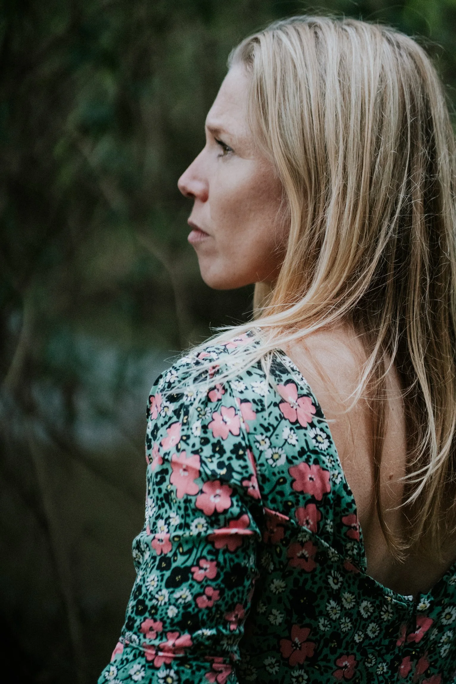 Abi Adams is standing, facing away from the camera - the image is taken behind her. There are trees in the background.