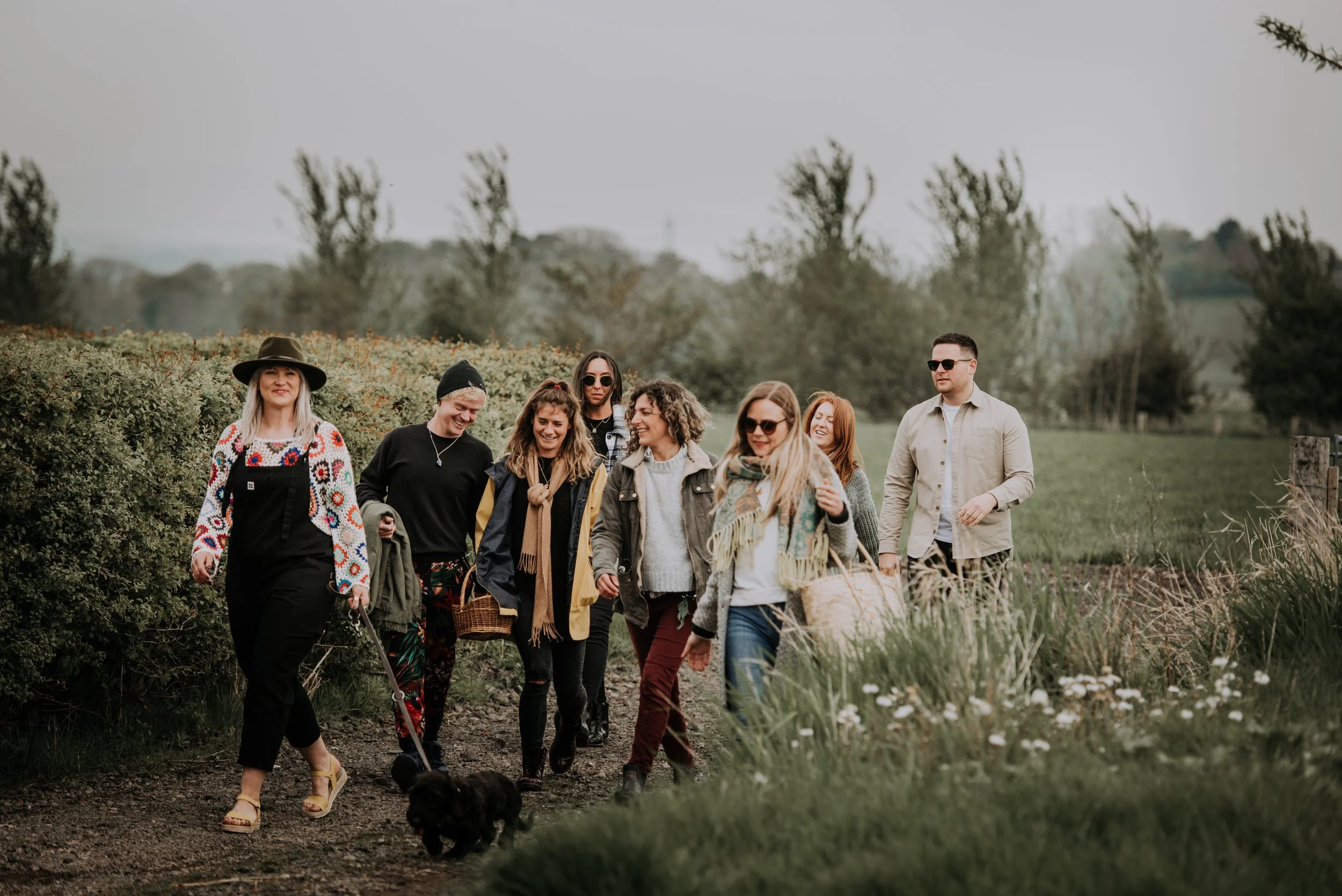 A group of women are outside and walking together. They are all laughing, smiling, and looking away from the camera.
