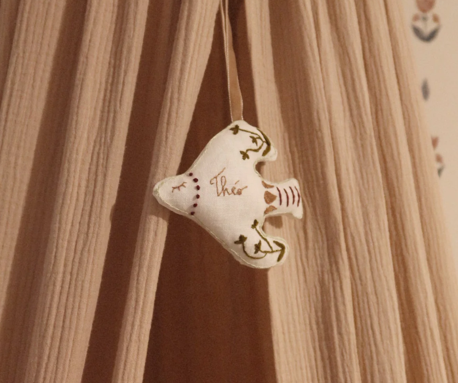 A fabric bird-shaped ornament hanging from a string against a wooden background.
