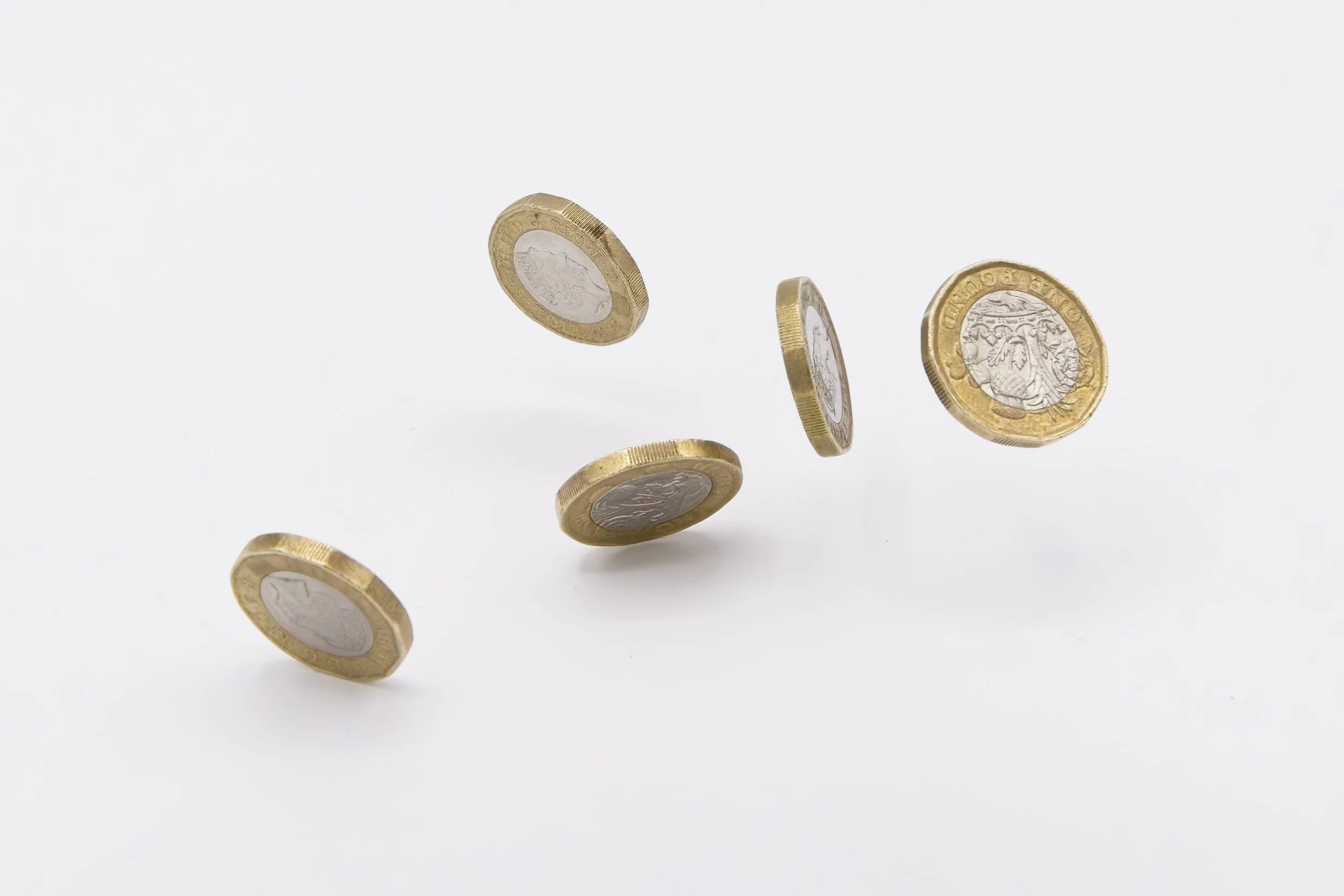 Five euro coins in mid-air against a white background.