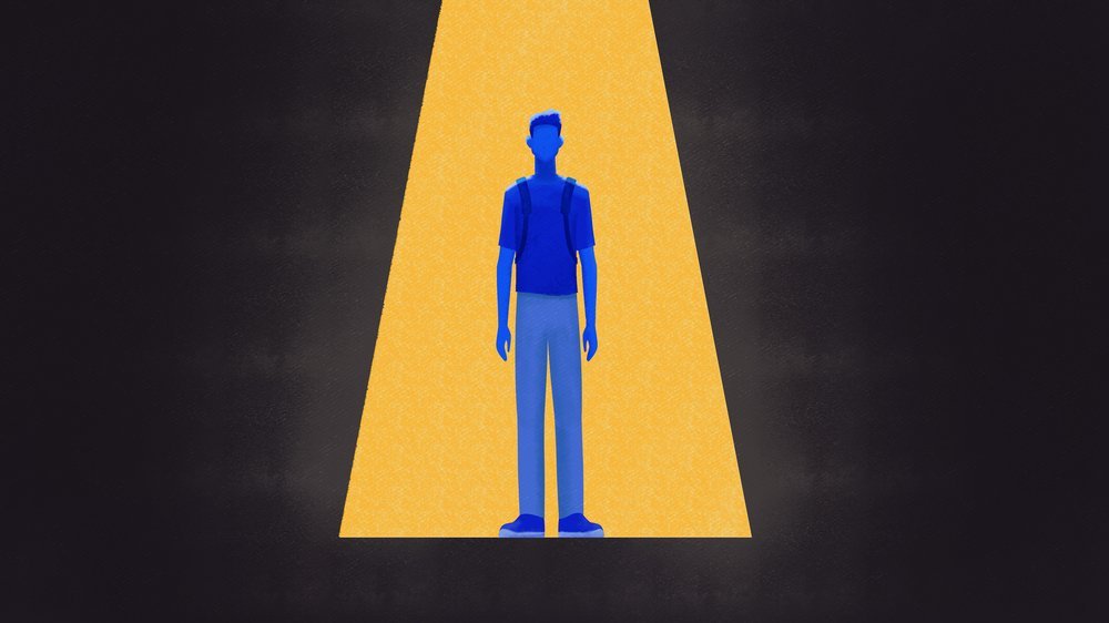 A person standing in a spotlight on a dark background.