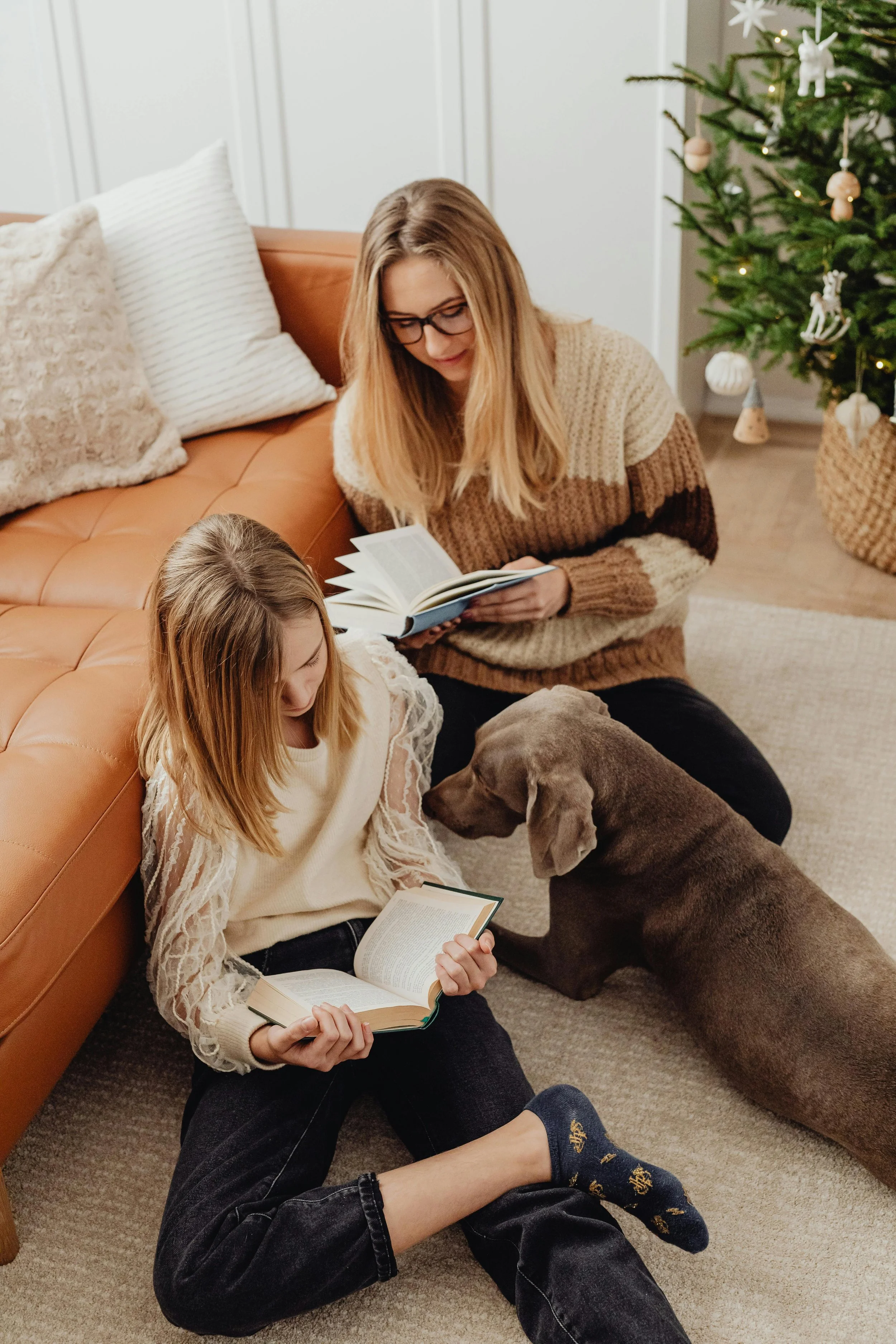 A mother and daughter sitting on the floor reading their own books alongside their dog, representing family and child animal-assisted therapy at Inside Out Therapy in Peoria, AZ