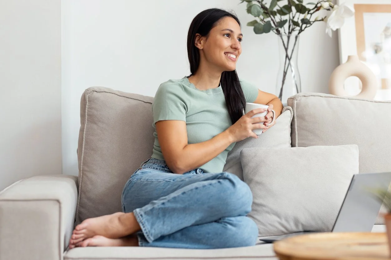 A woman sitting on a couch holding a mug and talking openly, representing adult therapy and EMDR treatment at Inside Out Therapy in Peoria, AZ