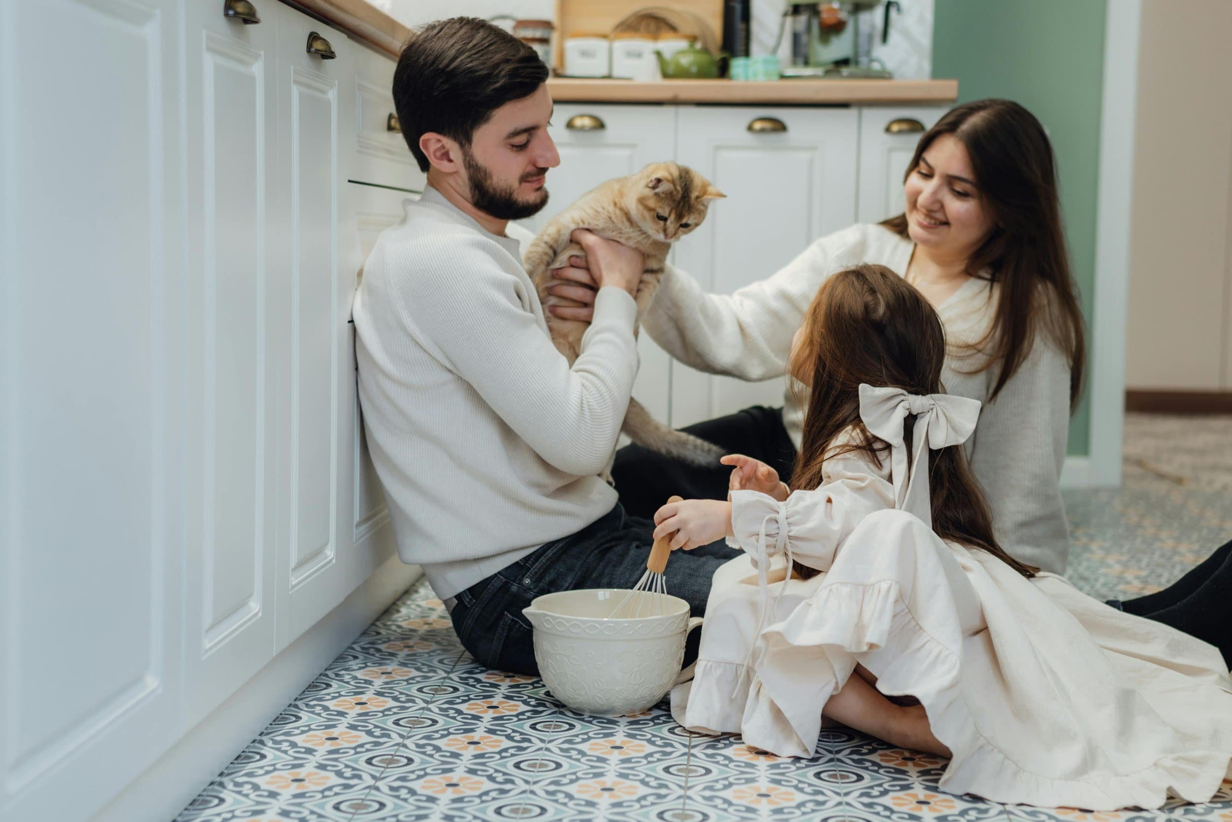 A young family sitting together on the kitchen floor with their cat, representing family connection and trauma therapy in Peoria, AZ