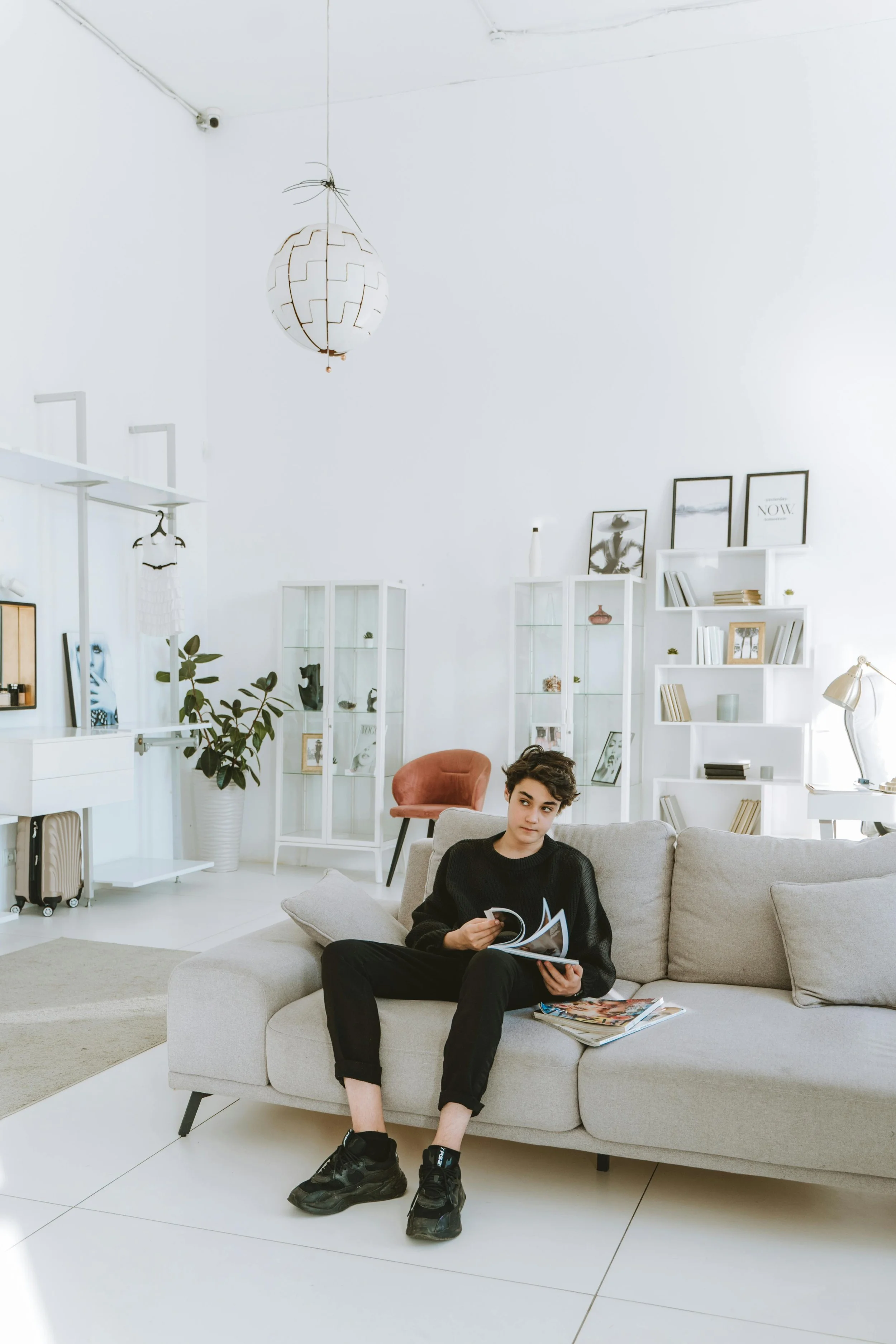 Teenage boy sitting relaxed on a couch looking through a magazine, representing a comfortable and low-pressure therapy experience for teens at Inside Out Therapy in Peoria Arizona