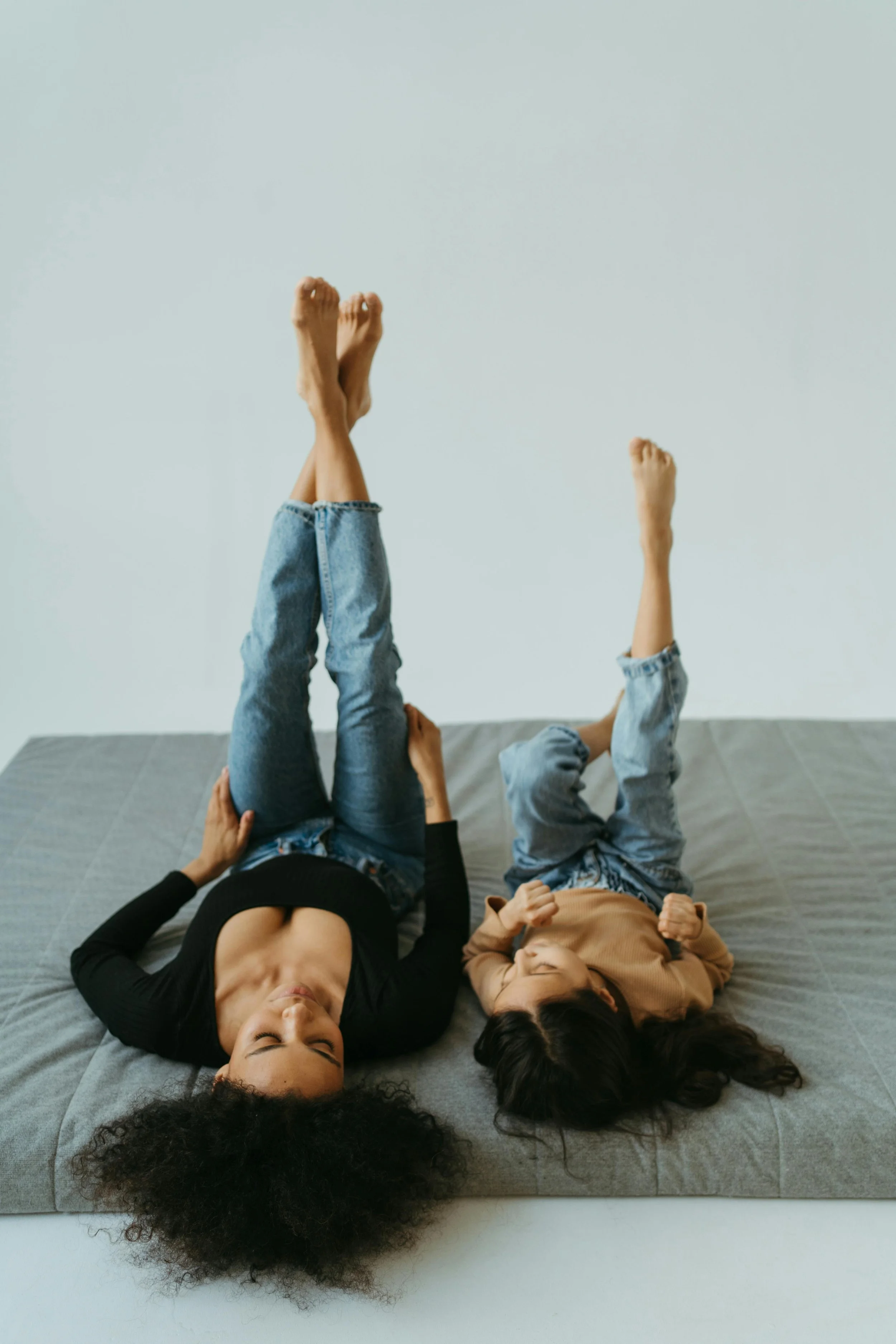 Mother and young daughter laying side by side across a bed with legs up, representing child therapy and emotional regulation support at Inside Out Therapy in Peoria Arizona