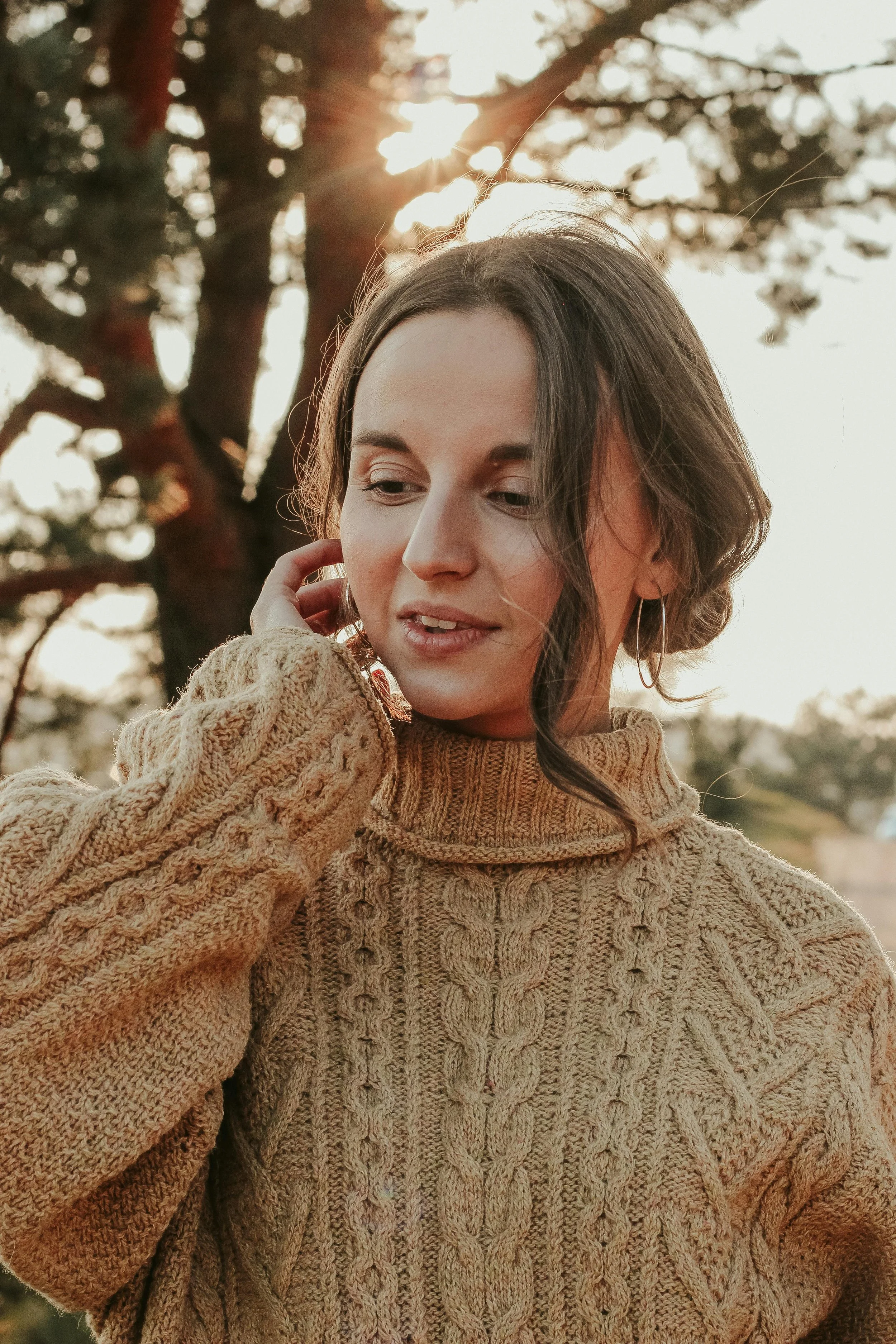 Woman standing outside tucking hair behind her ear with a thoughtful expression, representing anxiety and chronic stress therapy at Inside Out Therapy in Peoria Arizona