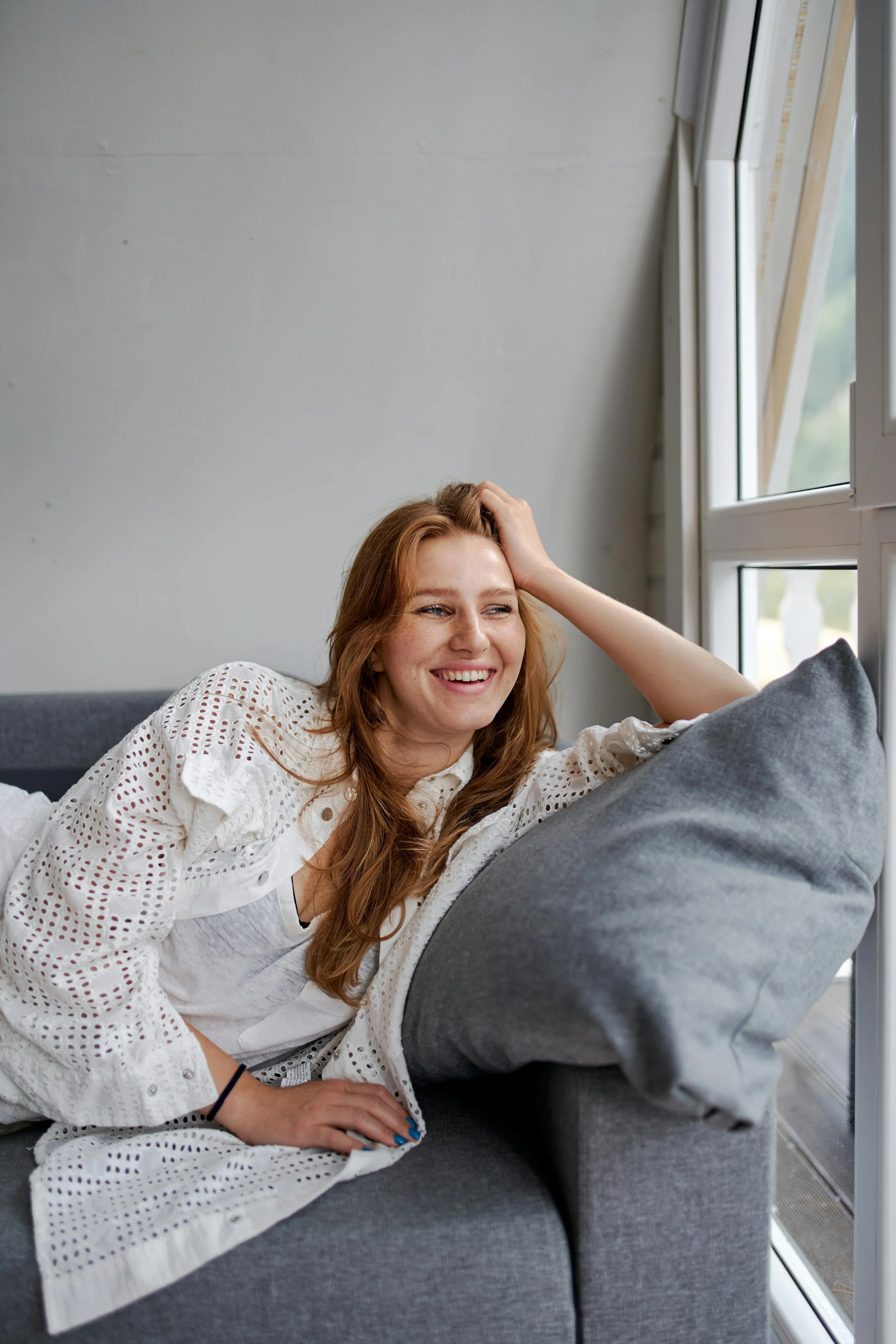 Woman sitting on couch resting her head on her hand and smiling, representing trauma and PTSD therapy at Inside Out Therapy in Peoria Arizona