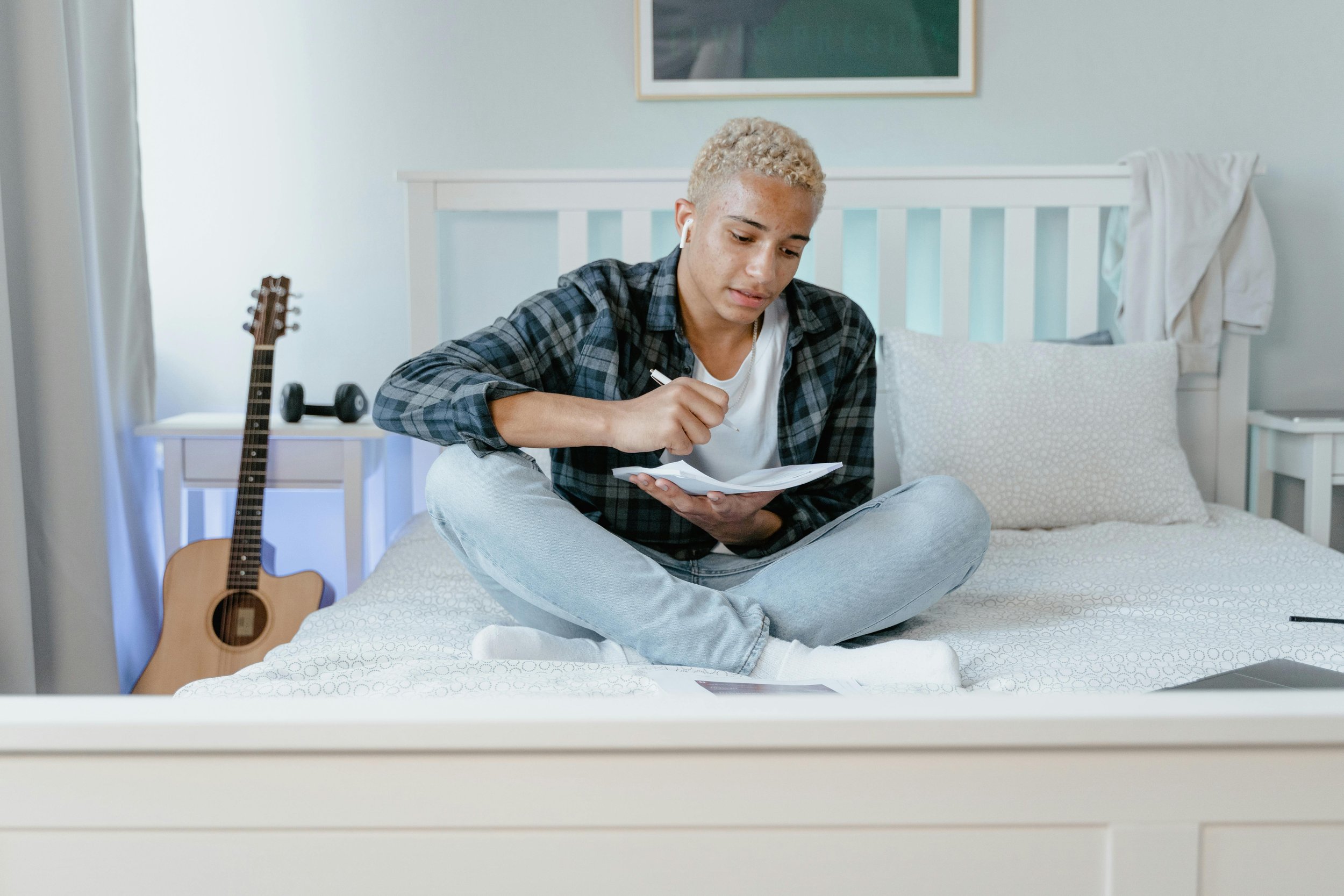 Teenager sitting cross-legged on a bed writing in a journal, representing trauma therapy for teens at Inside Out Therapy in Peoria Arizona
