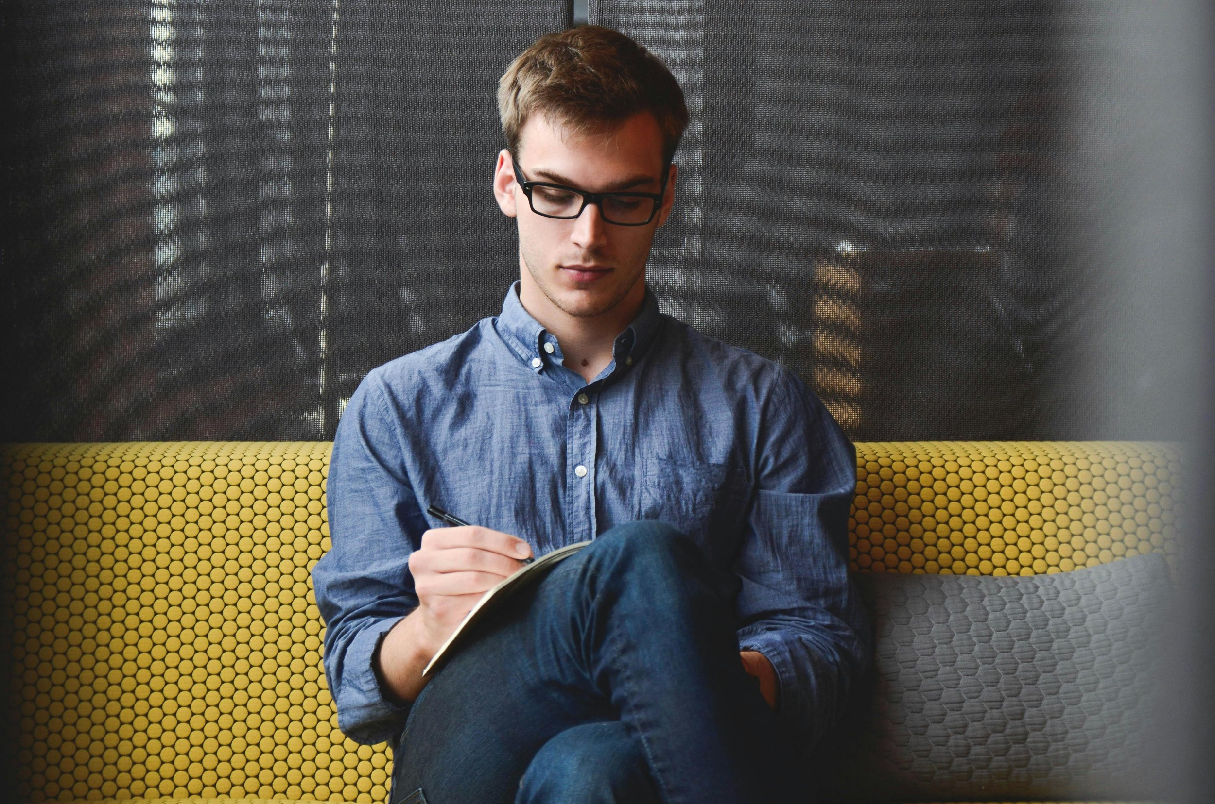 Man sitting on a couch writing, representing the reflective process of grief therapy at Inside Out Therapy in Peoria Arizona