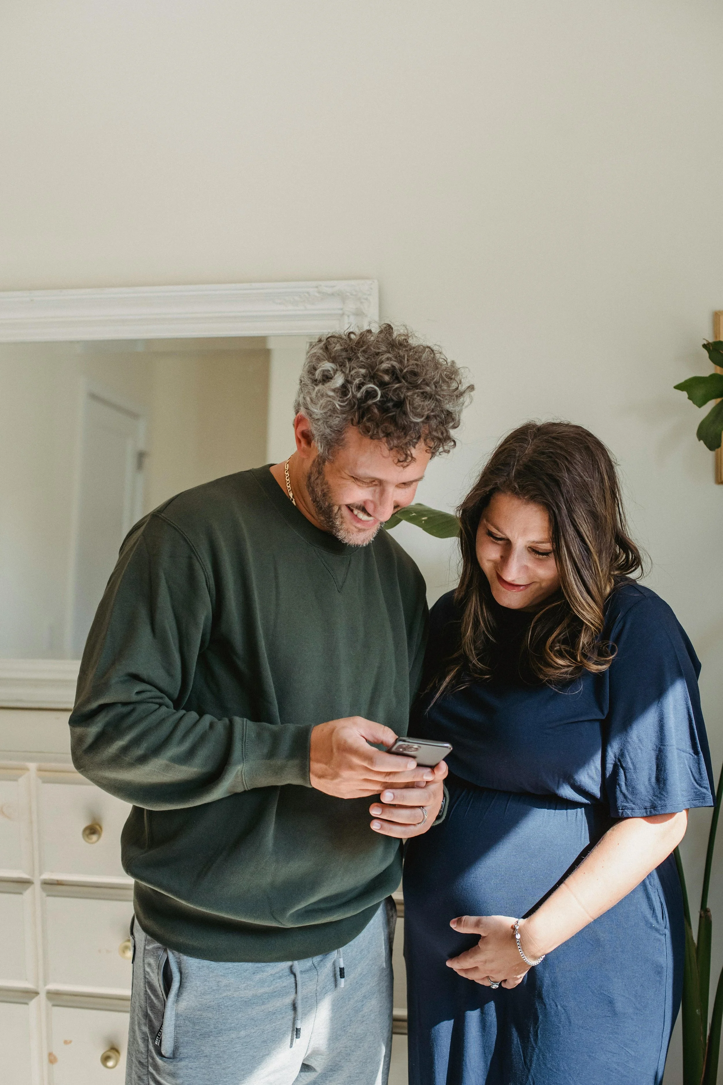 A pregnant woman and her partner looking at a phone together, representing perinatal and postpartum therapy for families near Surprise, AZ at Inside Out Therapy in Peoria