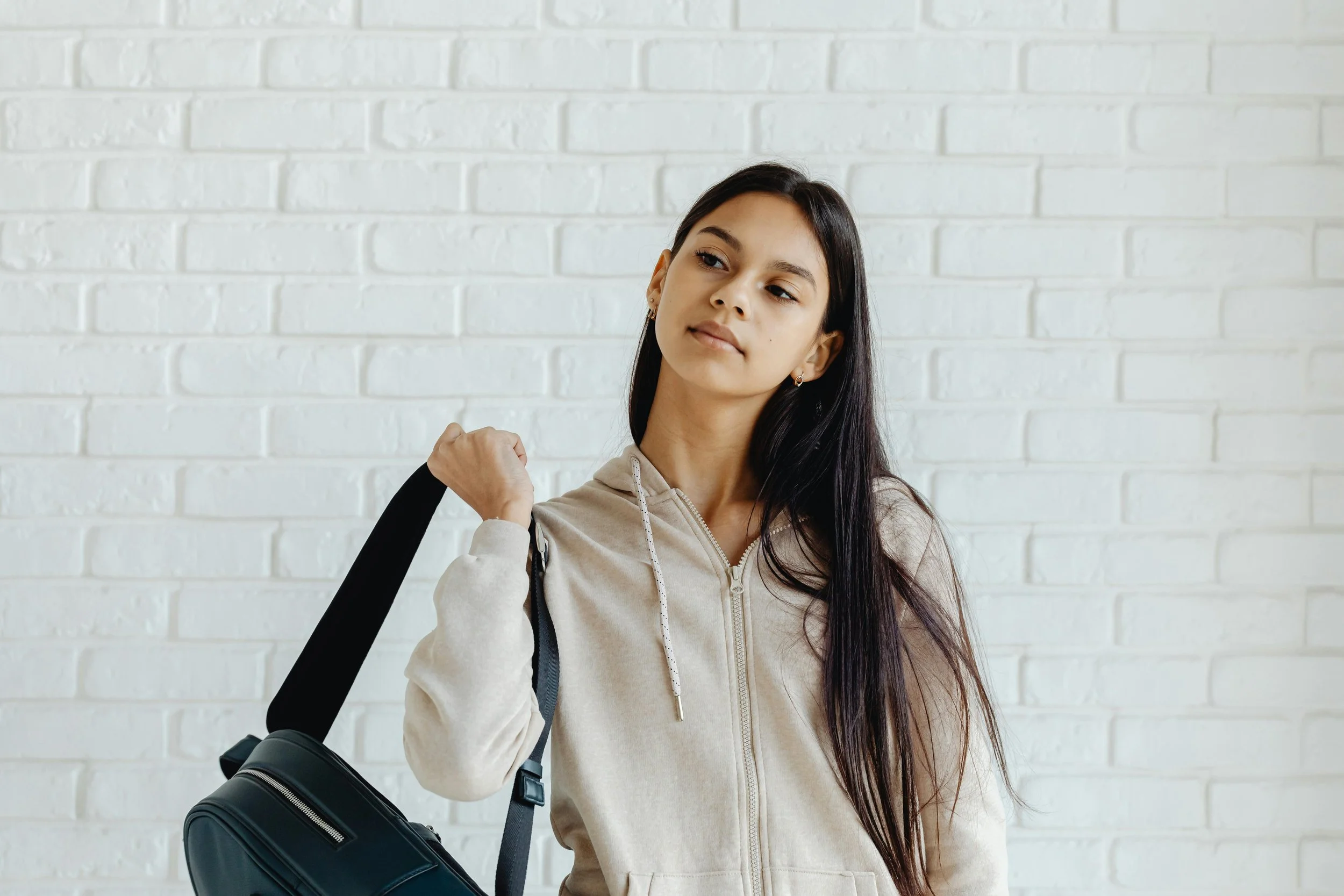 Teenage girl putting on her backpack in a school hallway, representing anxiety therapy for teens at Inside Out Therapy in Peoria Arizona