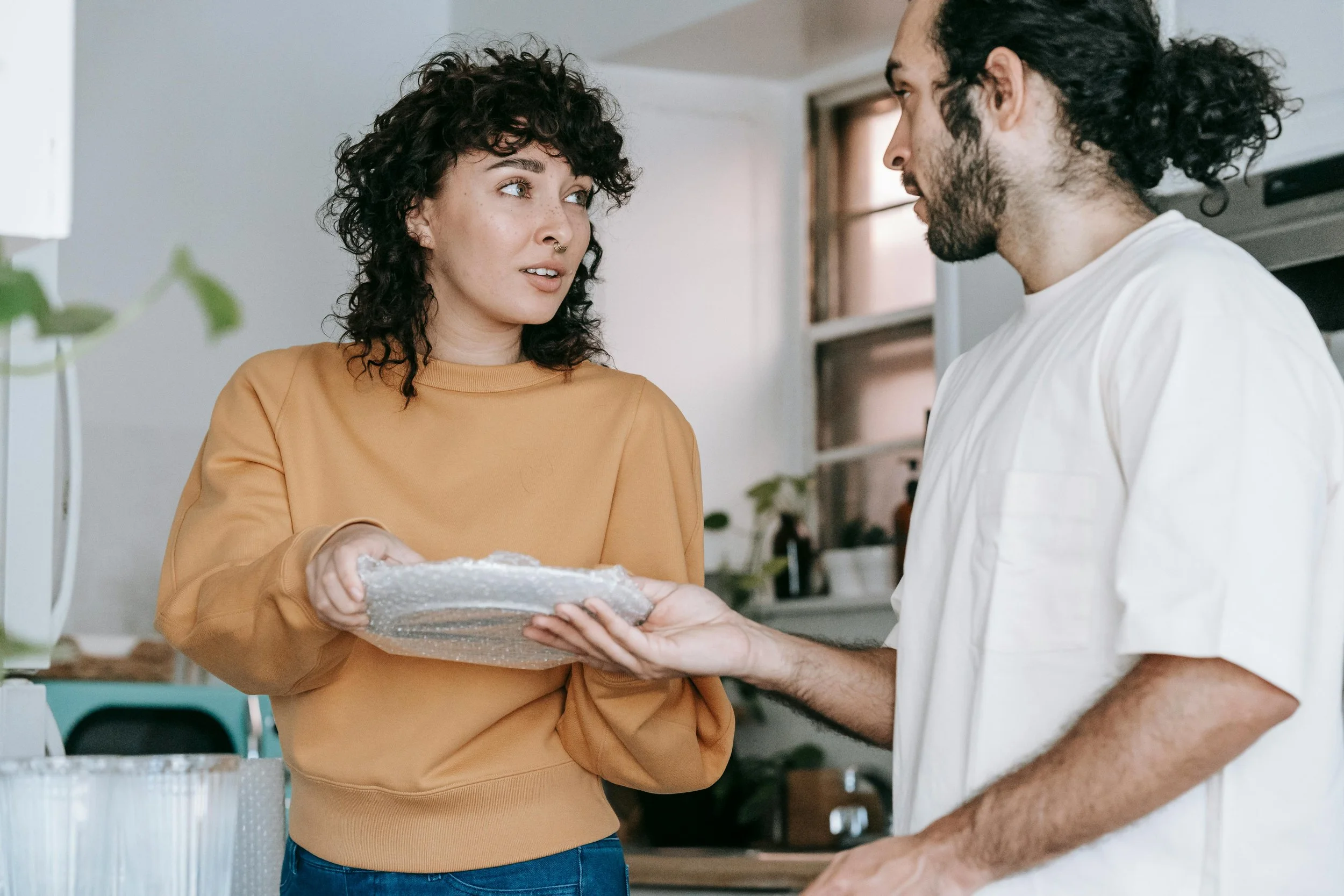 Man and woman unpacking dishes together and talking, representing therapy for life transitions and unrecognized grief at Inside Out Therapy in Peoria Arizona
