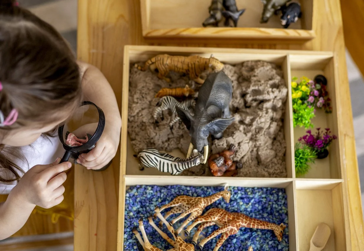 A child sitting on the floor engaged in play with small figures, representing children's sand tray therapy and emotional regulation at Inside Out Therapy in Peoria, AZ