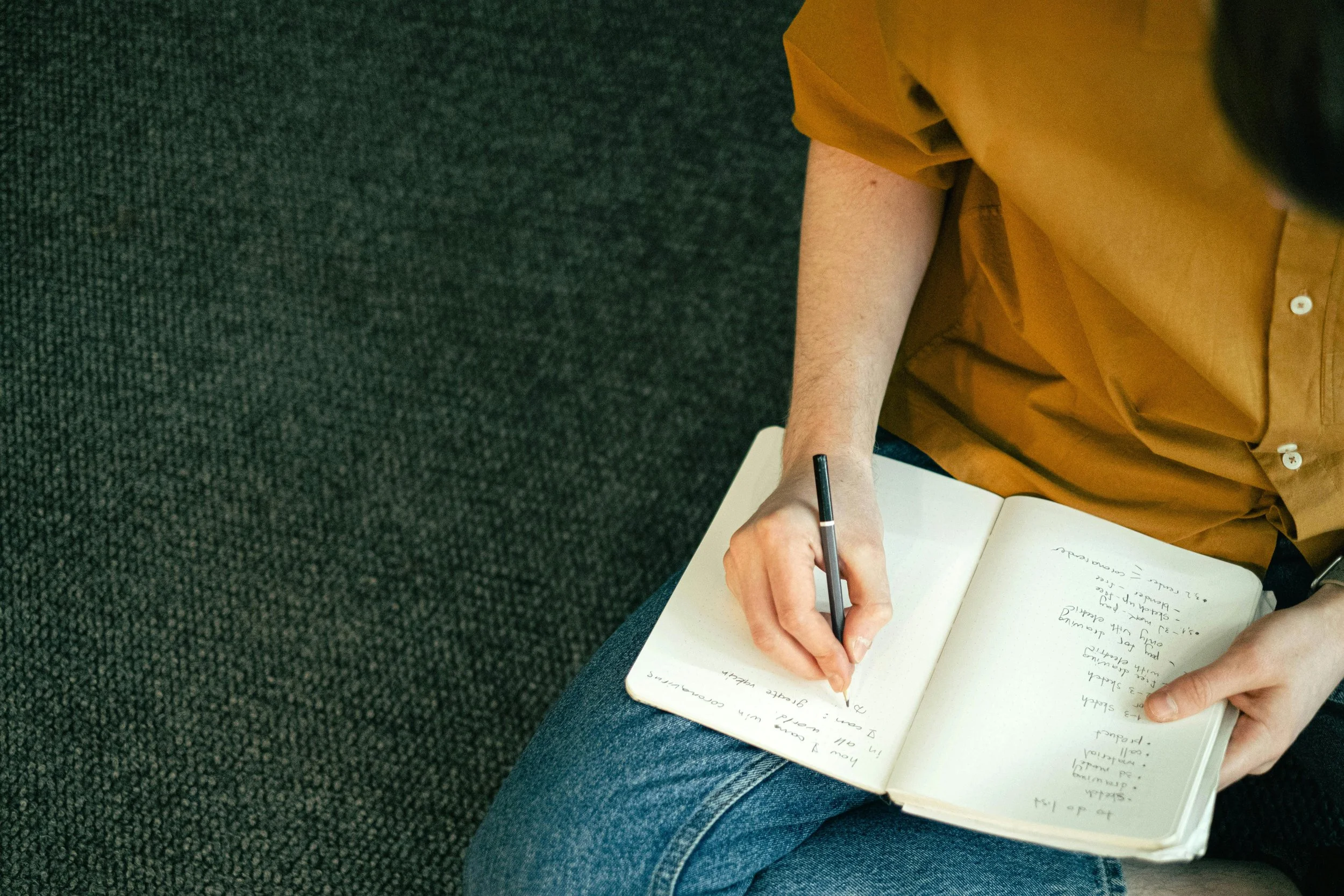 A person sitting on a couch writing in a notebook, representing in-person therapy sessions at Inside Out Therapy and Consulting serving the West Valley from Peoria, AZ