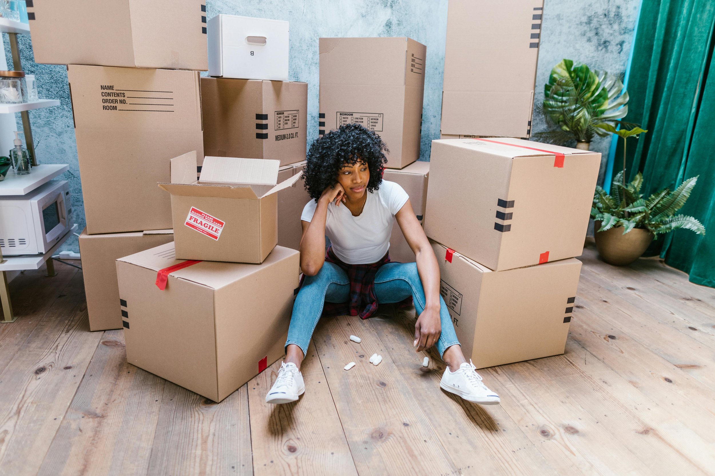 Woman sitting on the floor surrounded by moving boxes, representing therapy for grief, loss, and life transitions at Inside Out Therapy in Peoria Arizona