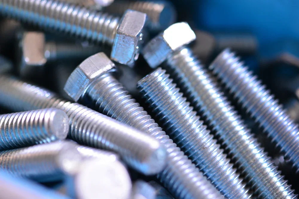 Close-up of shiny metal bolts with hexagonal heads and threaded shafts.