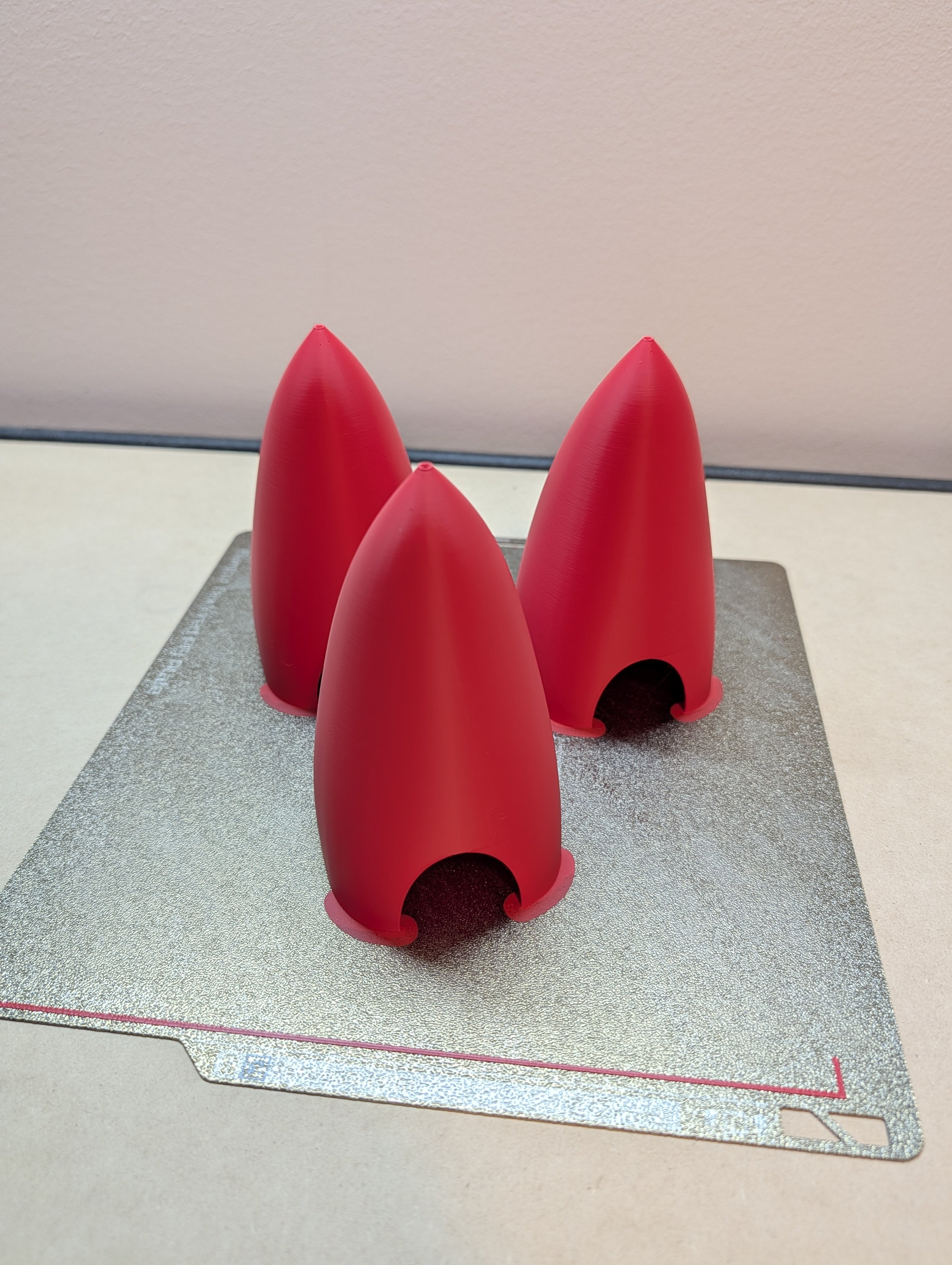 Three red rocket-shaped objects placed on a silver cutting board.
