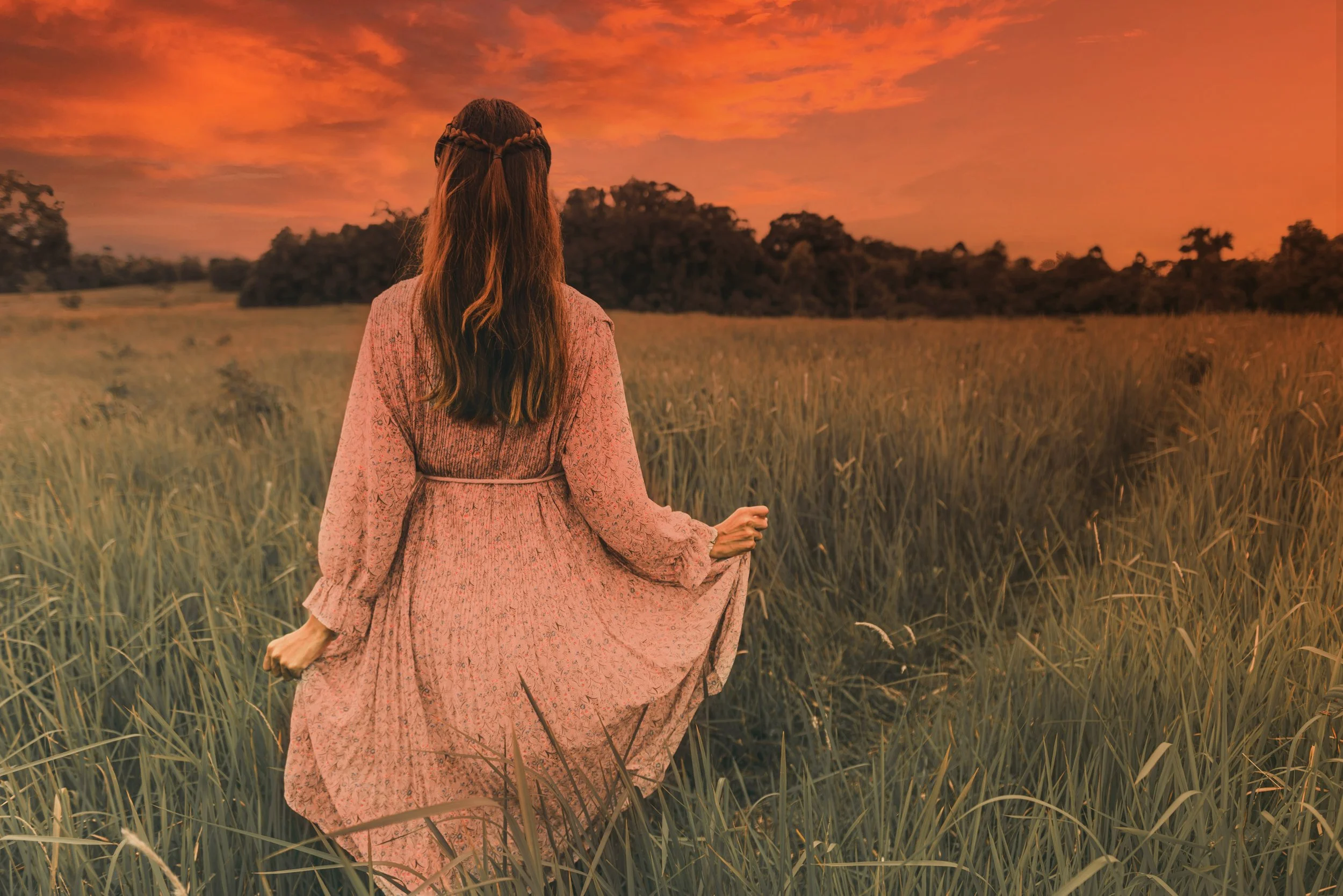 Femme marchant paisiblement dans la nature au coucher du soleil, représentant l’apaisement du stress et le retour à l’équilibre intérieur grâce à l’hypnose.