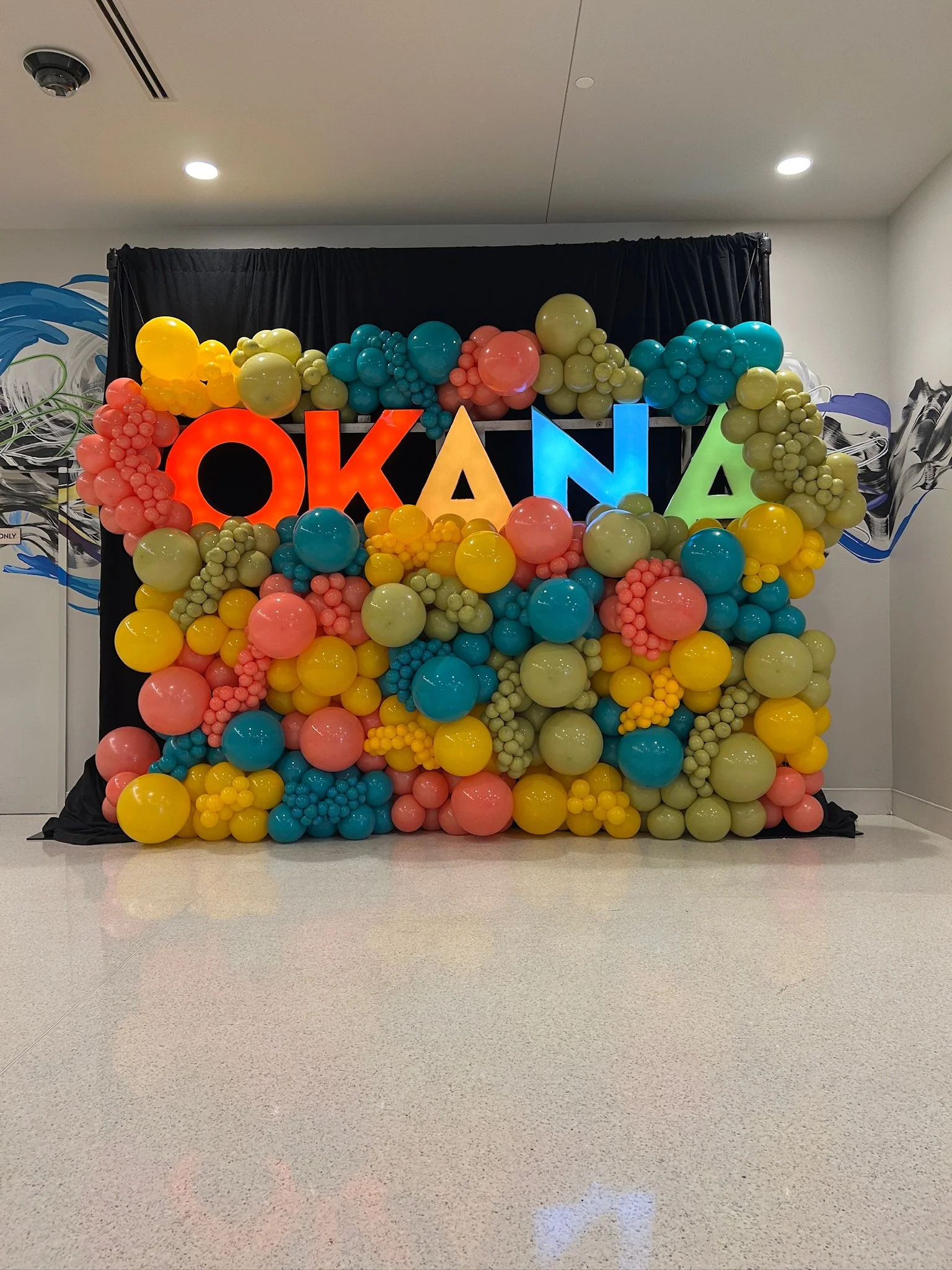 Colorful balloon decoration with the word 'OKANA' spelled out in large colorful letters.
