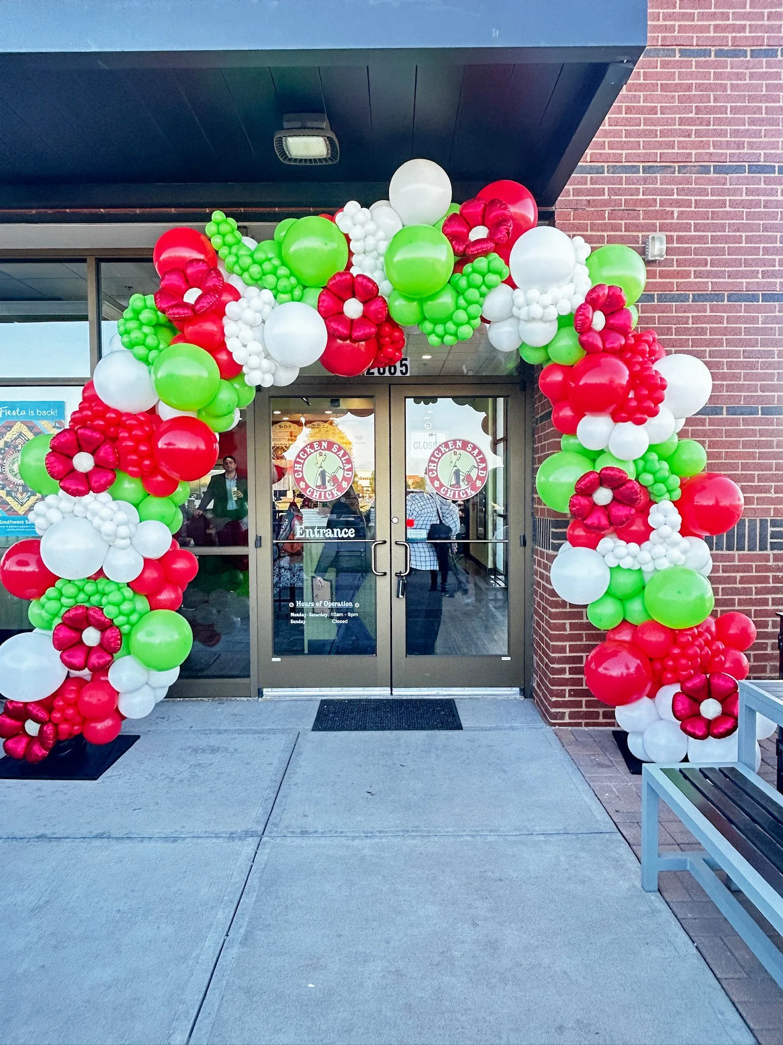 Decorative balloon arch in red, green, and white colors over the entrance of a chicken restaurant.