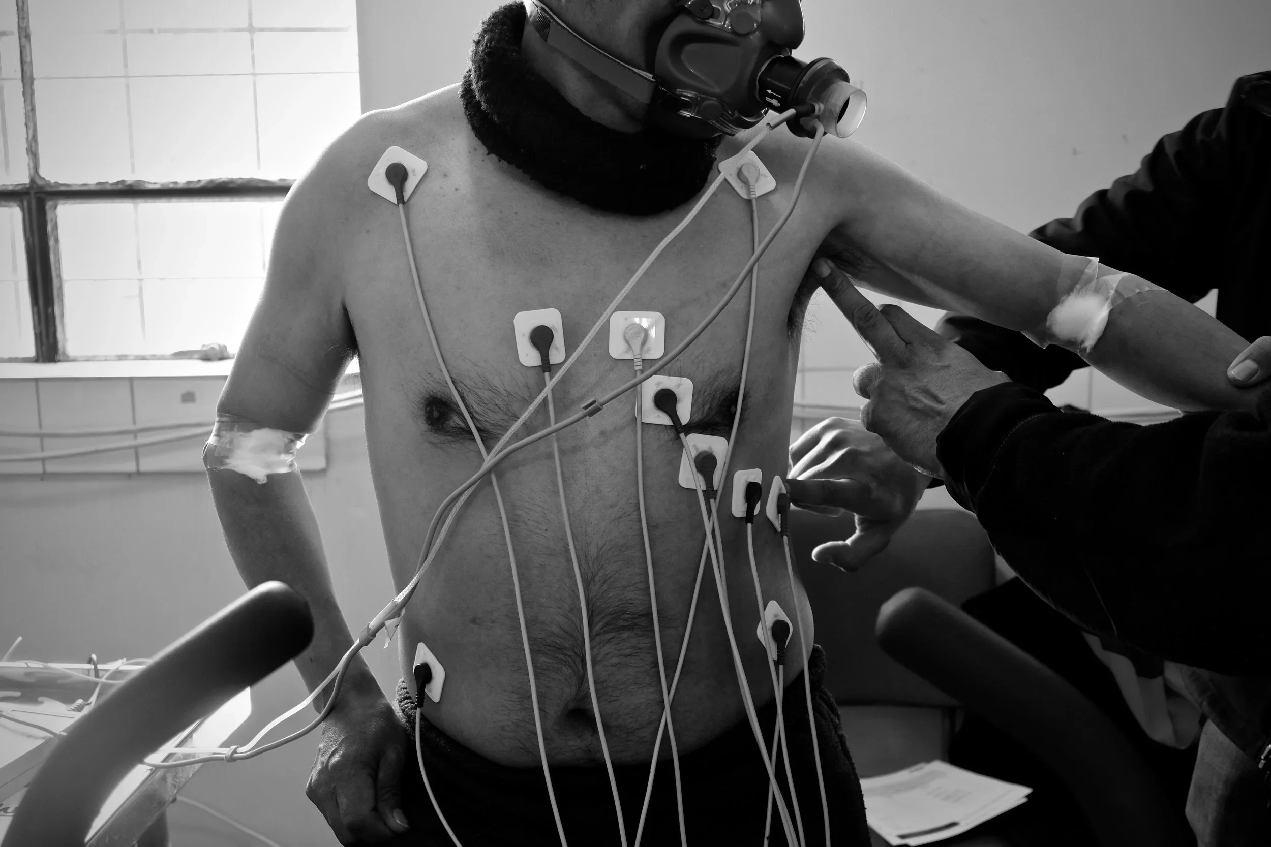 Participants are outfitted with body monitors and other devices prior to their stationary bike sessions.