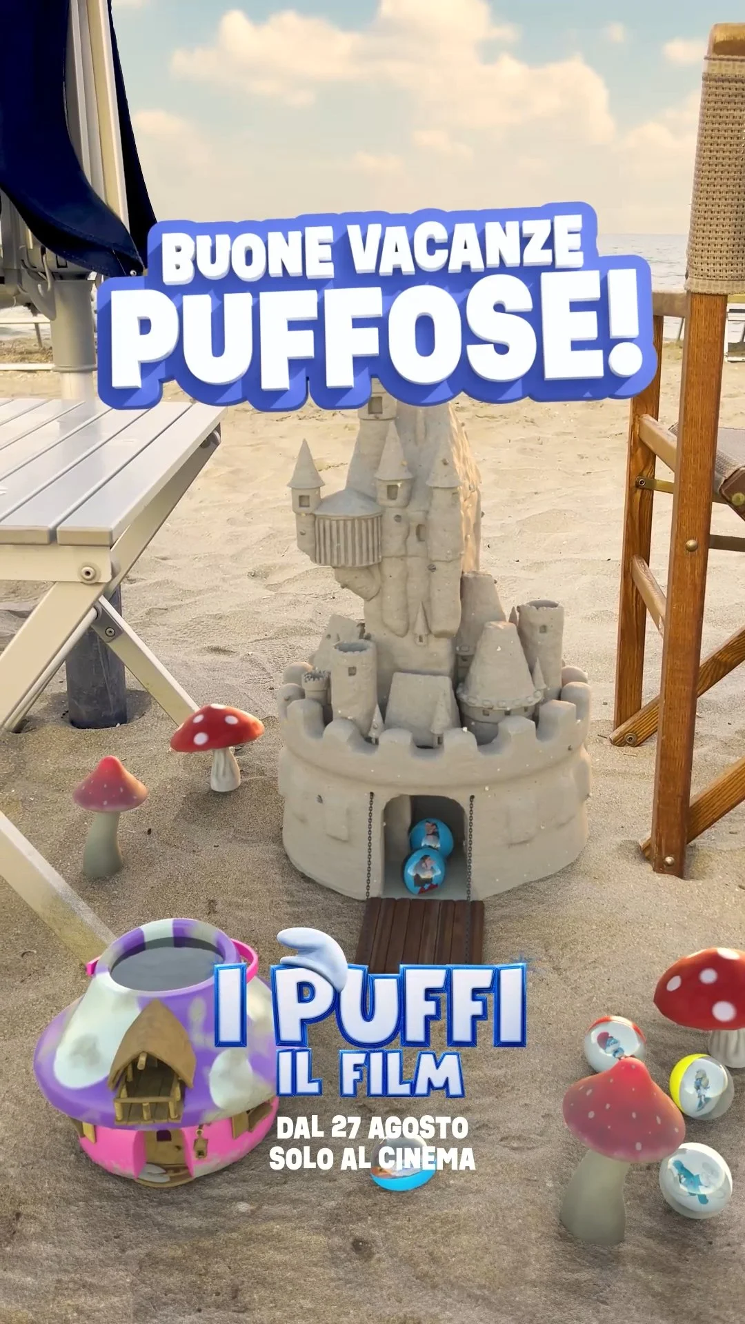 Messaggio promozionale per il film "I Puffi" con un castello di sabbia, funghi di plastica, casetta di champignon e decorazioni marittime sulla spiaggia.