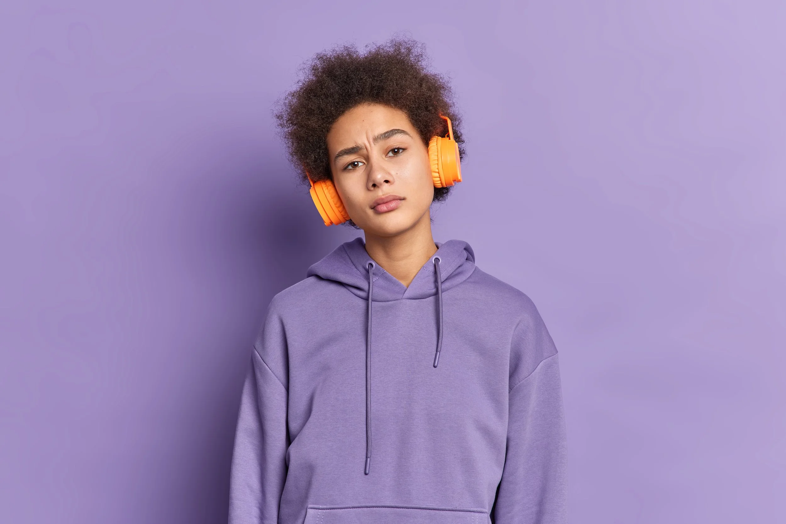 serious-african-american-millennial-girl-listens-audio-track-via-stereo-headphones-has-curly-bushy-hair-wears-purple-hoodie.jpg