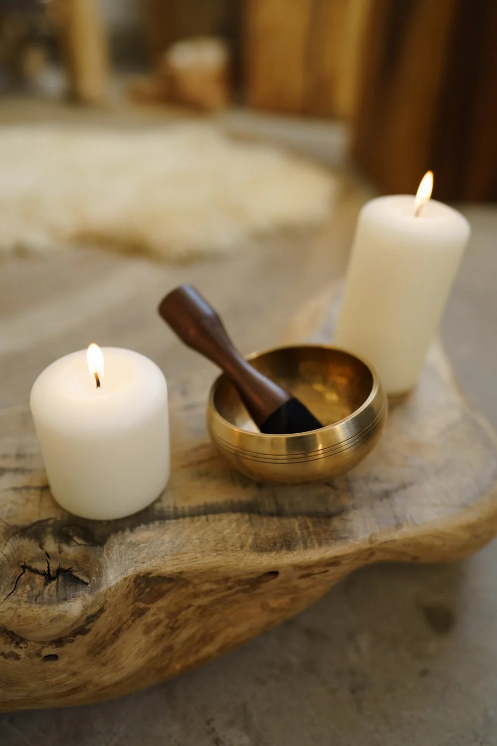 Singin bowl and two lit candles positioned on piece of reclaimed wood