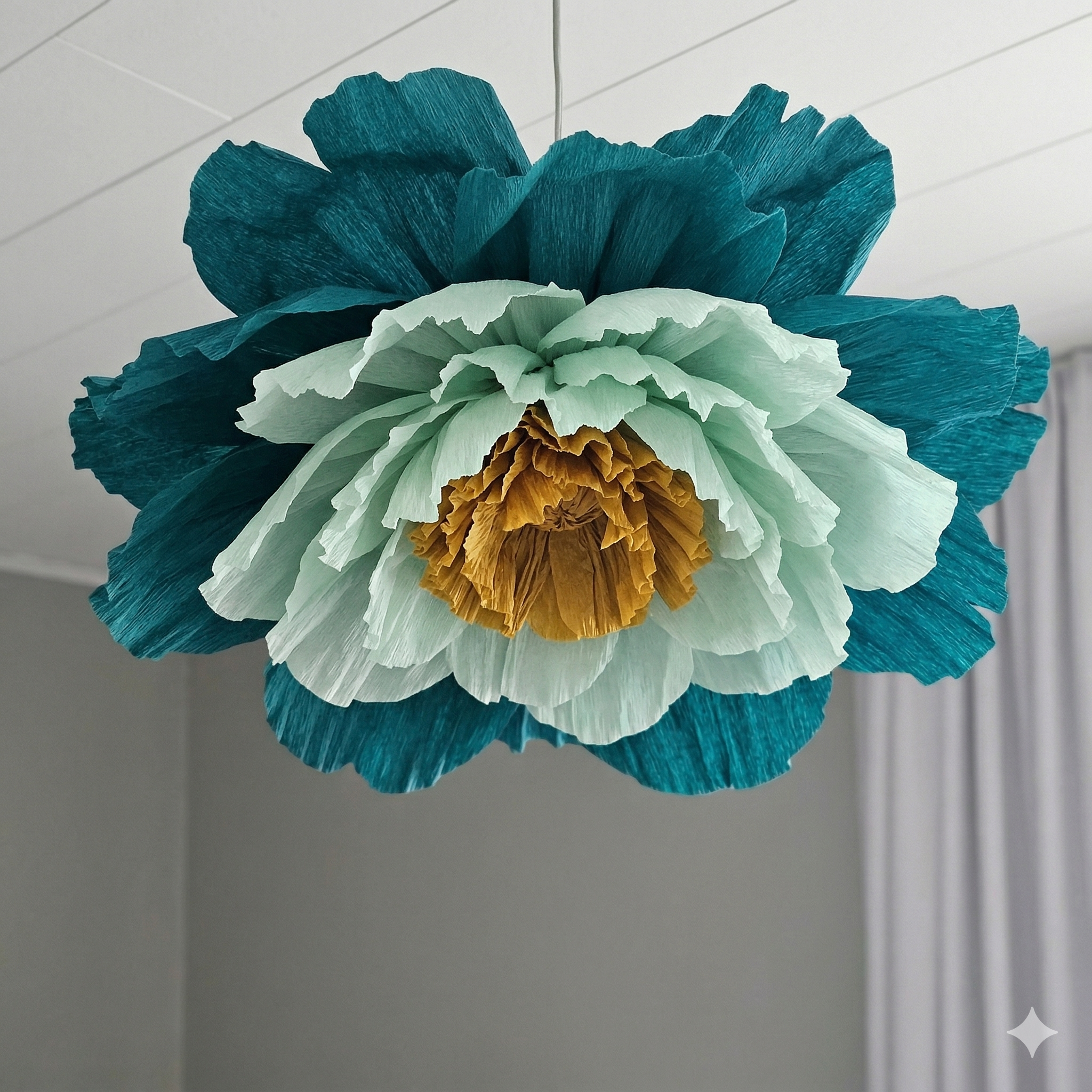 Colorful paper flower decoration hanging from the ceiling in a room.