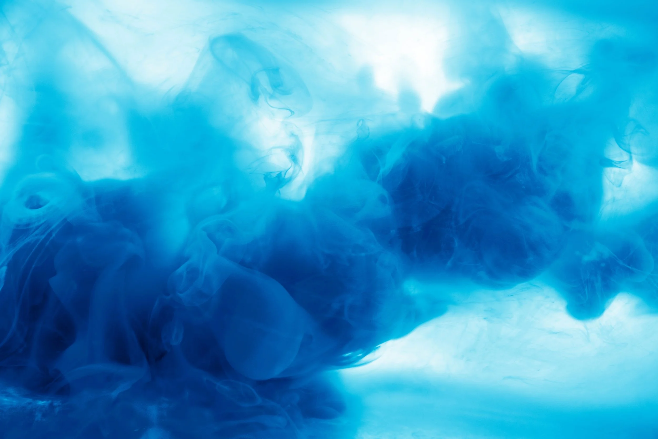 Blue swirling ink or dye diffusing in water.