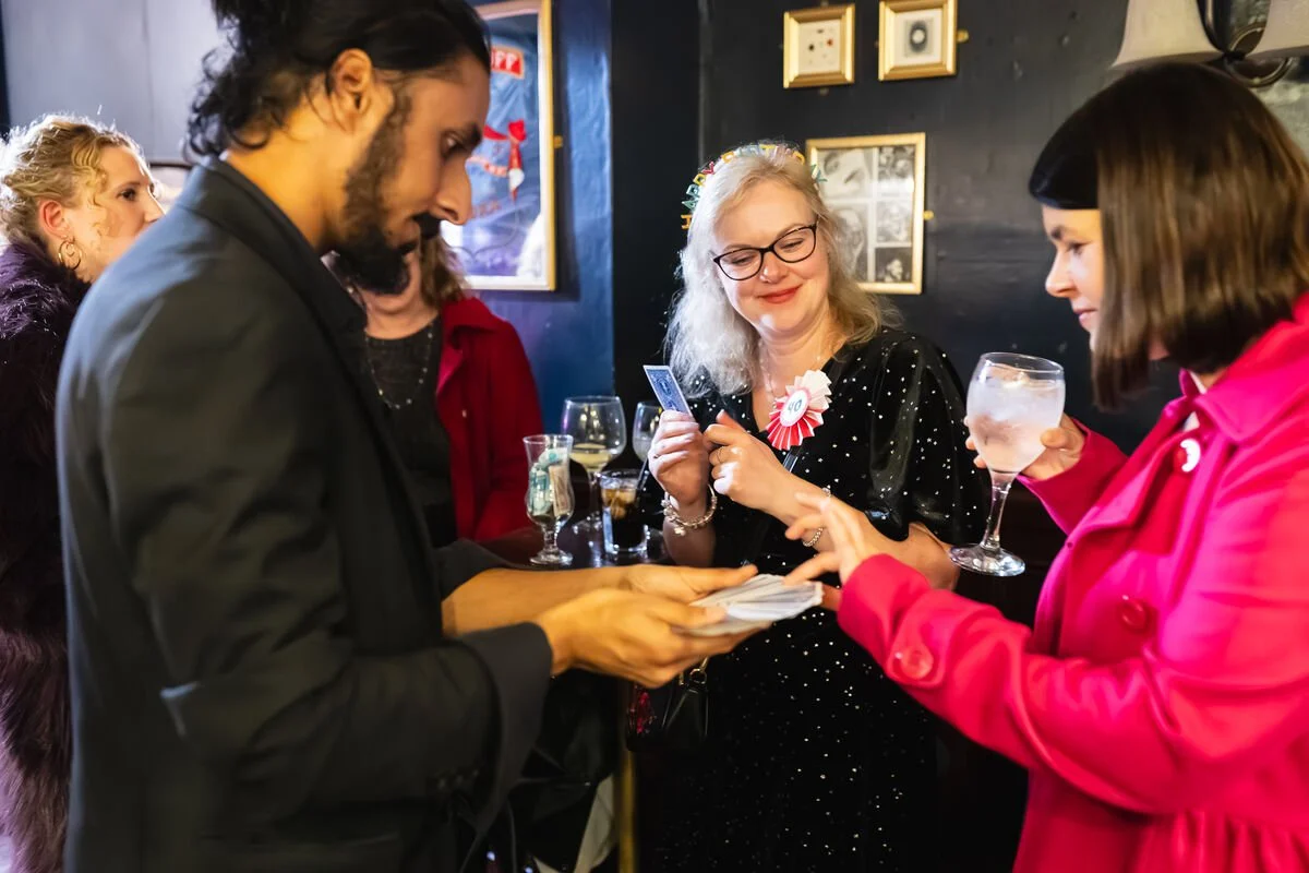 People at a celebration or party, exchanging cards and drinks in a lively setting.