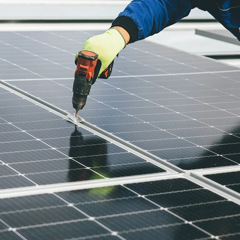 Close up of a hand drilling into a solar panel frame