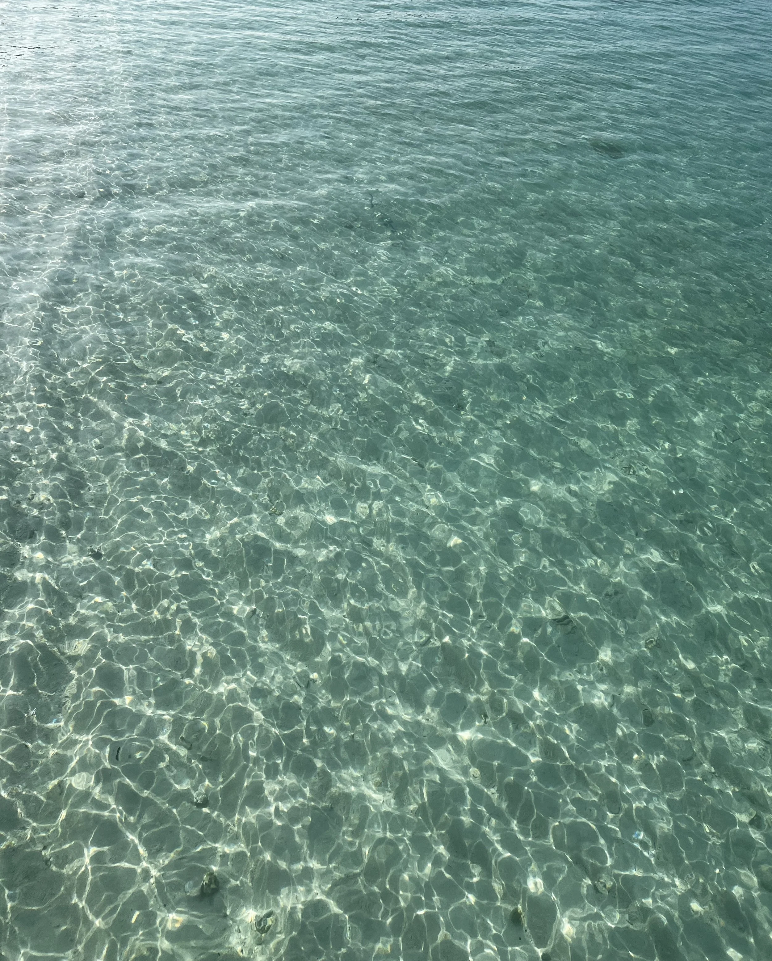 Clear turquoise water with sunlight reflecting off the surface.