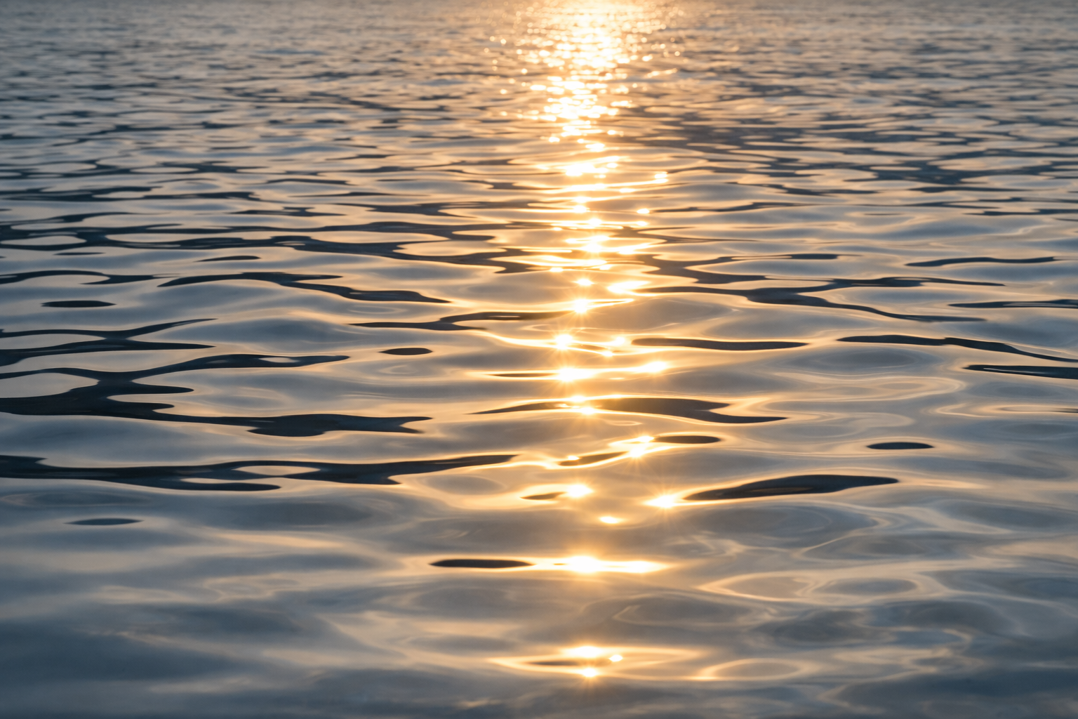 Sunset reflecting on calm ocean water with gentle ripples.